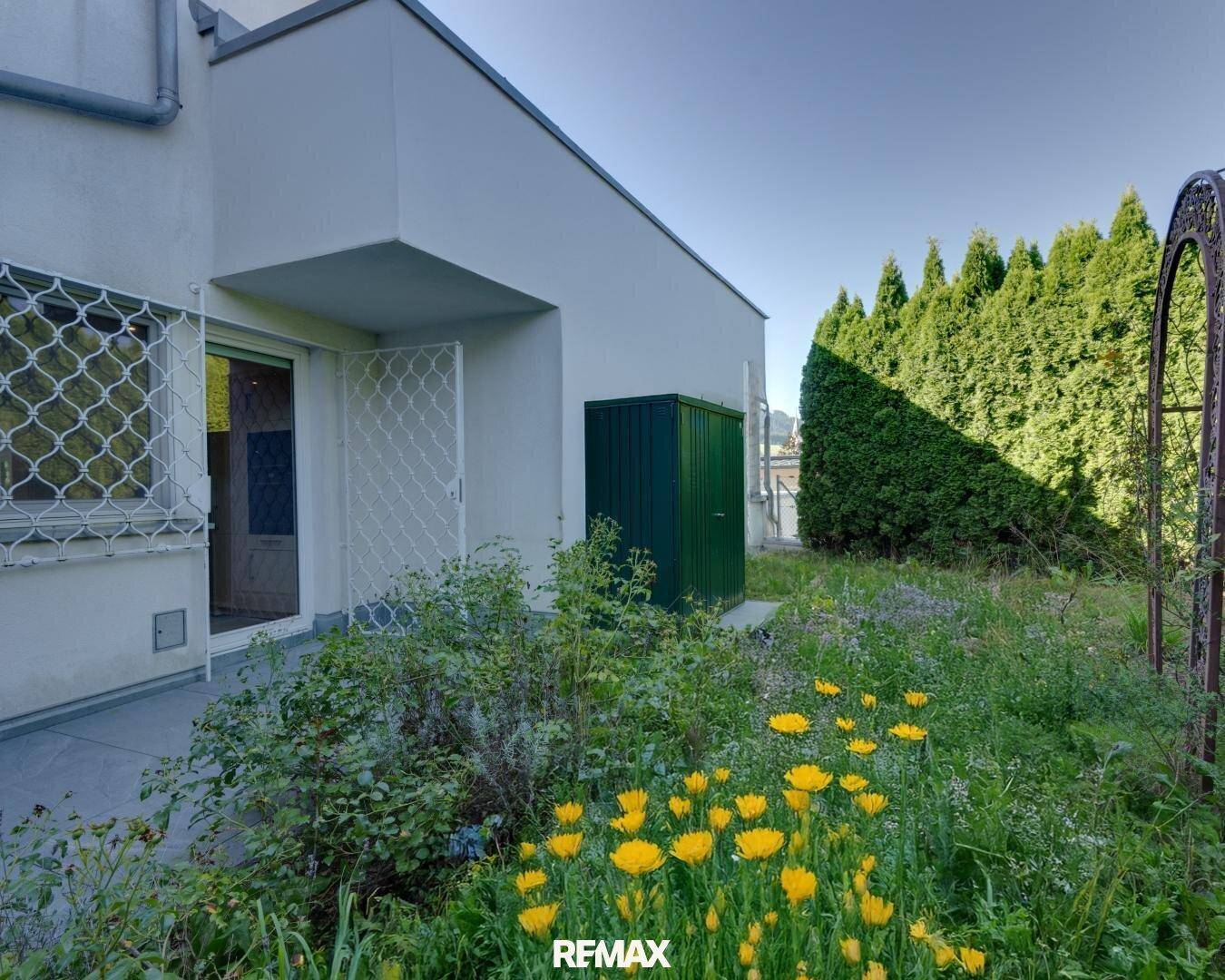 Kleiner Gartenbereich mit bunten Blumen, Sträuchern und einem praktischen Gartenschuppen.