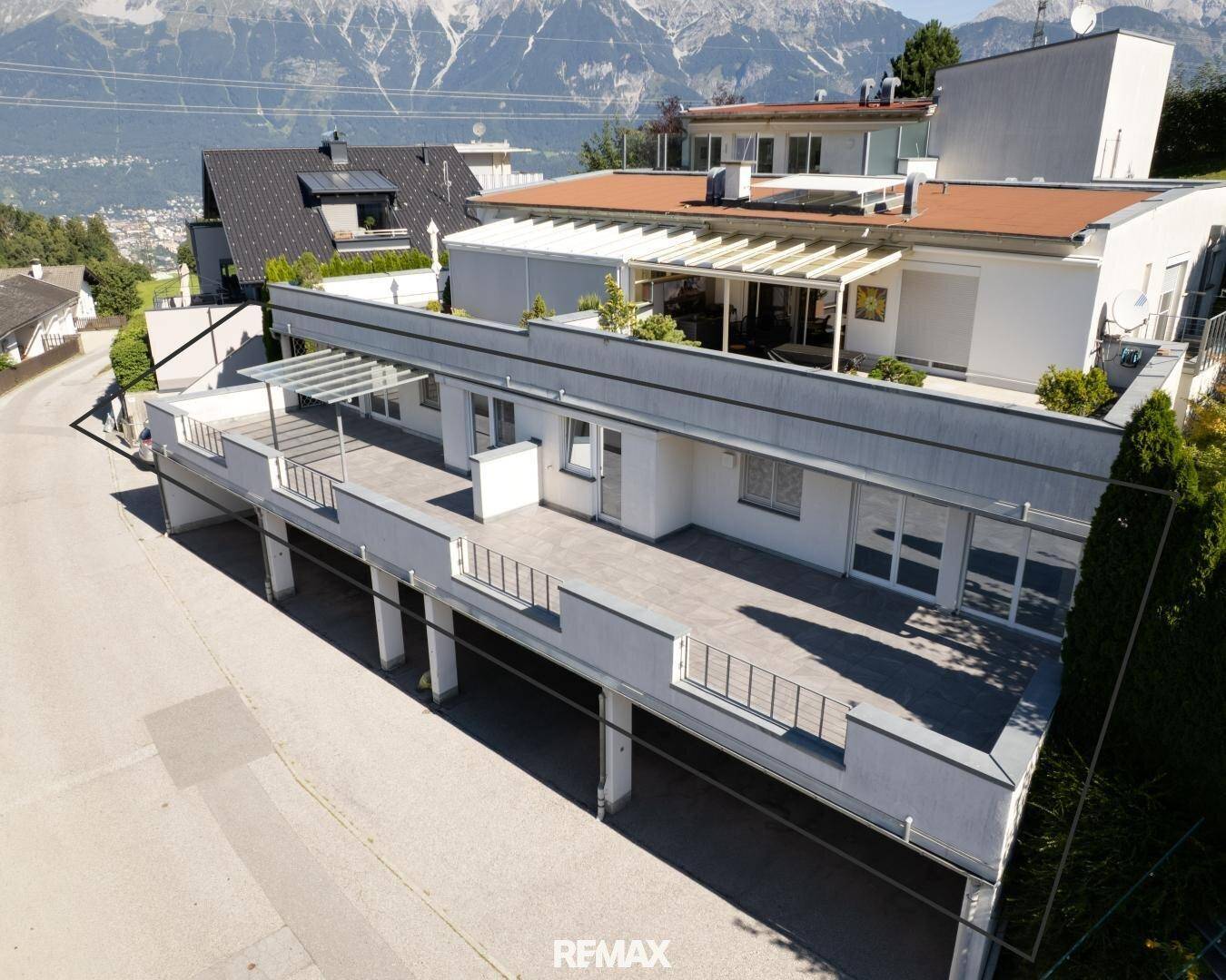 Ansicht des modernen Gebäudes mit weitläufigen Terrassenflächen und integrierten Garagen.