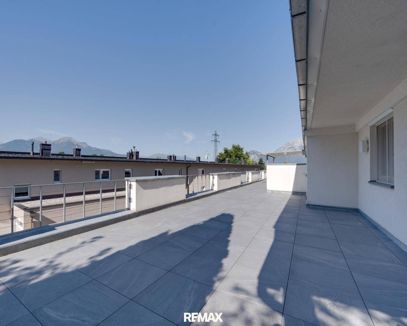 Weitläufige, geflieste Terrasse mit Metallgeländer und Panoramablick auf die umliegenden Berge.