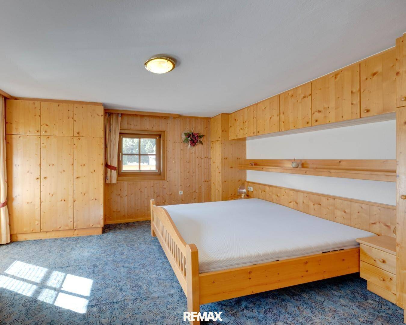 Geräumiges Schlafzimmer mit Einbauschränken aus Holz und Teppichboden.