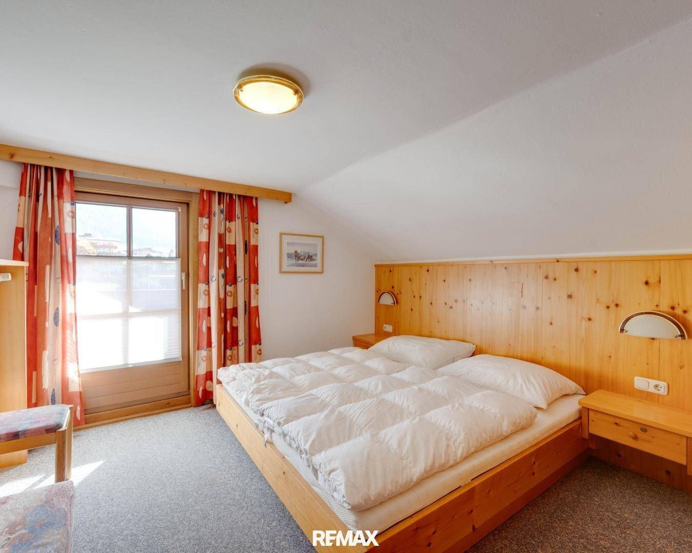 Gemütliches Schlafzimmer im Dachgeschoss mit schräger Decke und Balkonzugang.