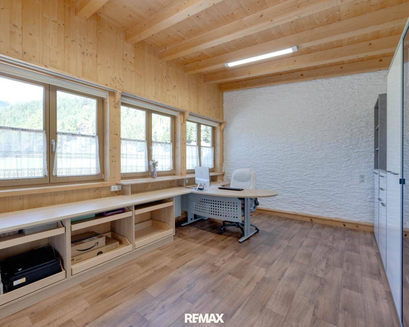 Helles Büro mit Holzbalkendecke, großen Fenstern und funktionalen Möbeln für konzentriertes Arbeiten.