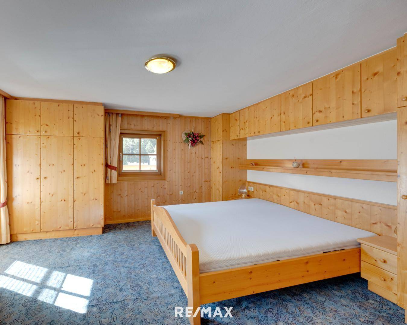Traditionelles Schlafzimmer mit Holzvertäfelung, Einbauschränken und einem Doppelbett im alpinen Stil.