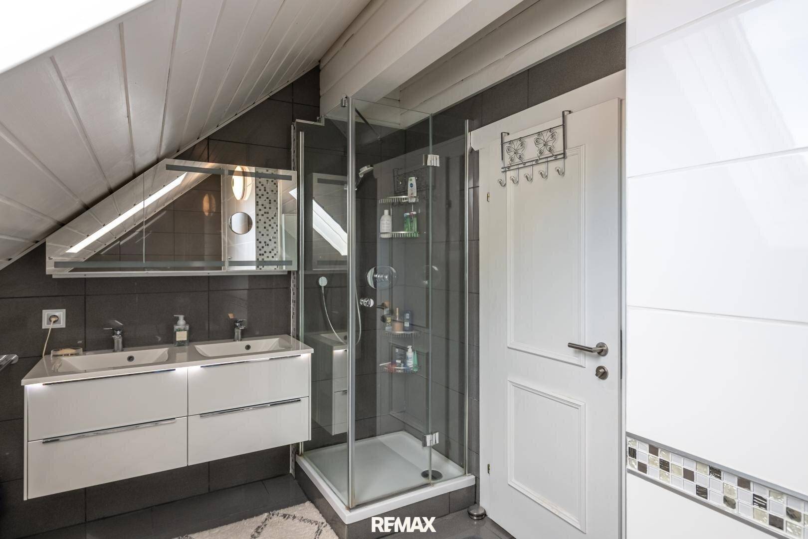 Modernes Badezimmer mit begehbarer Dusche, Doppelwaschbecken und Dachschräge.