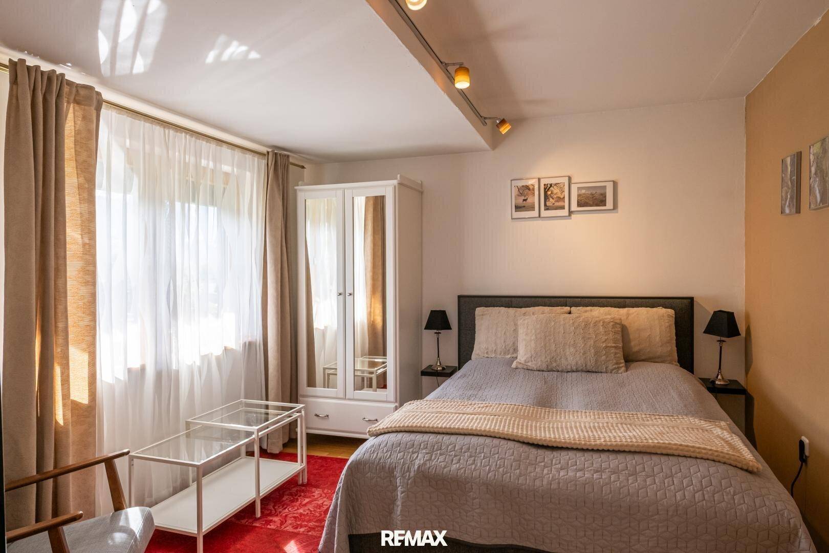 Gemütliches Schlafzimmer mit Doppelbett, Kleiderschrank und hellem Fenster.