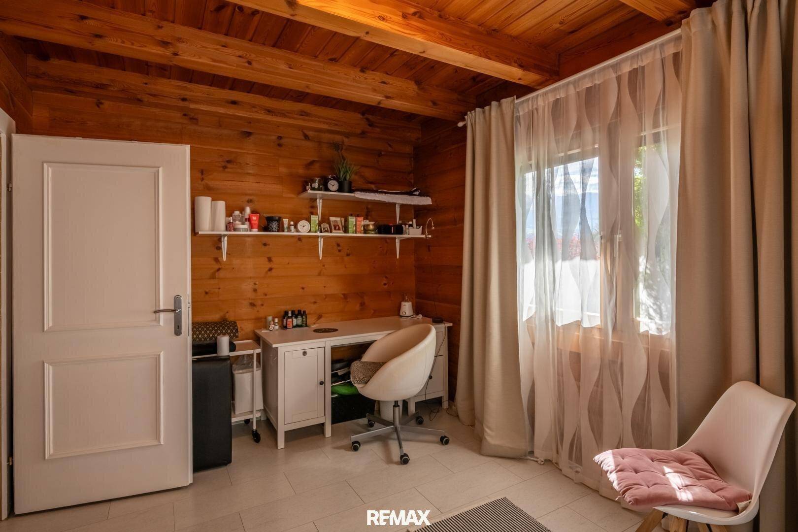 Helles Arbeitszimmer mit Holzwänden, Schreibtisch und Blick ins Grüne.