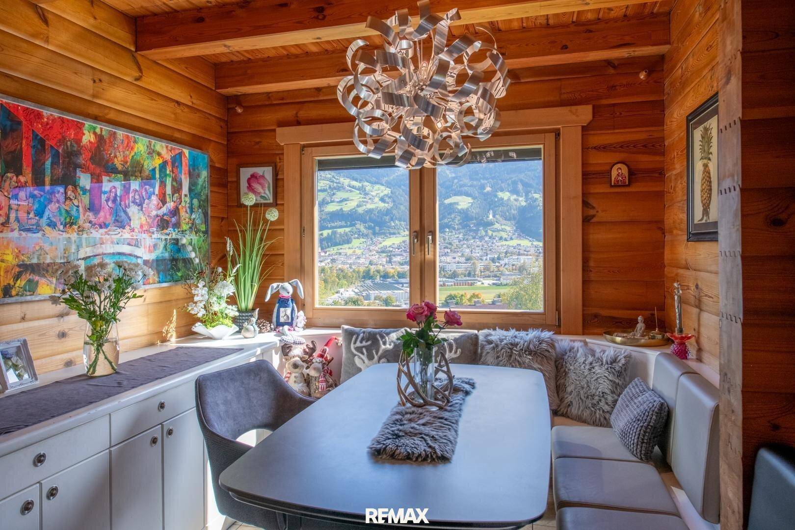 Essbereich mit Holzwänden, modernem Kronleuchter und Panoramablick auf die Berglandschaft.