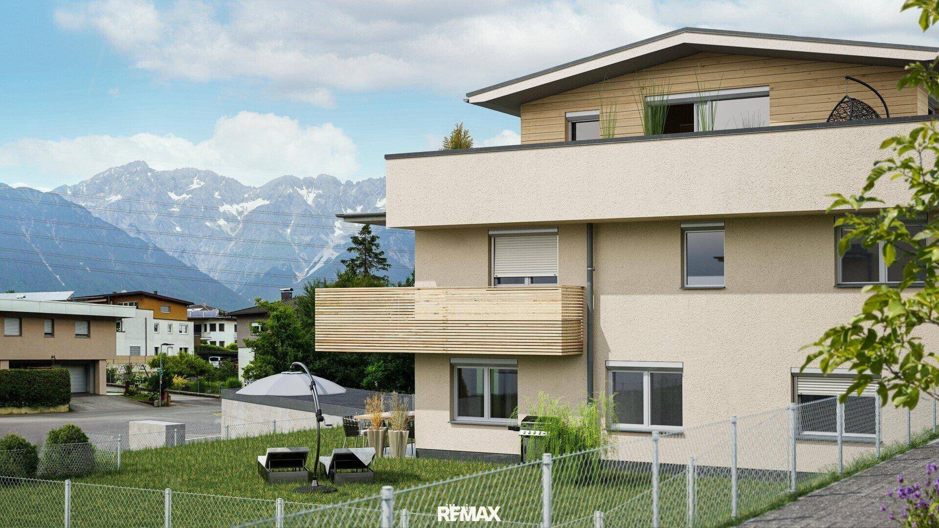Moderne Wohnanlage mit Balkon, Gartenbereich und beeindruckendem Bergblick unter blauem Himmel.
