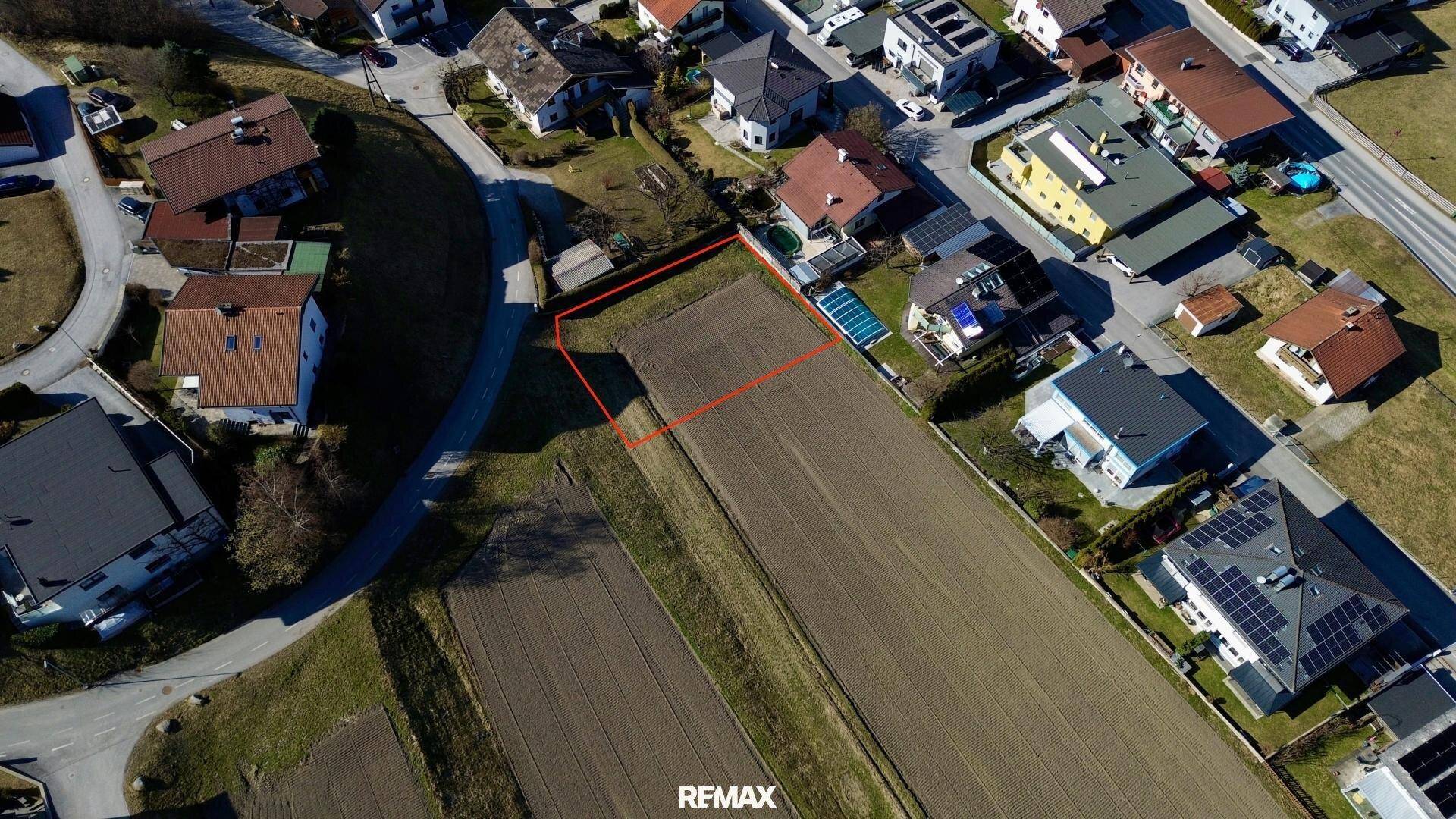 Luftaufnahme eines markierten Baugrundstücks, umgeben von Wohnhäusern und einer Straße.