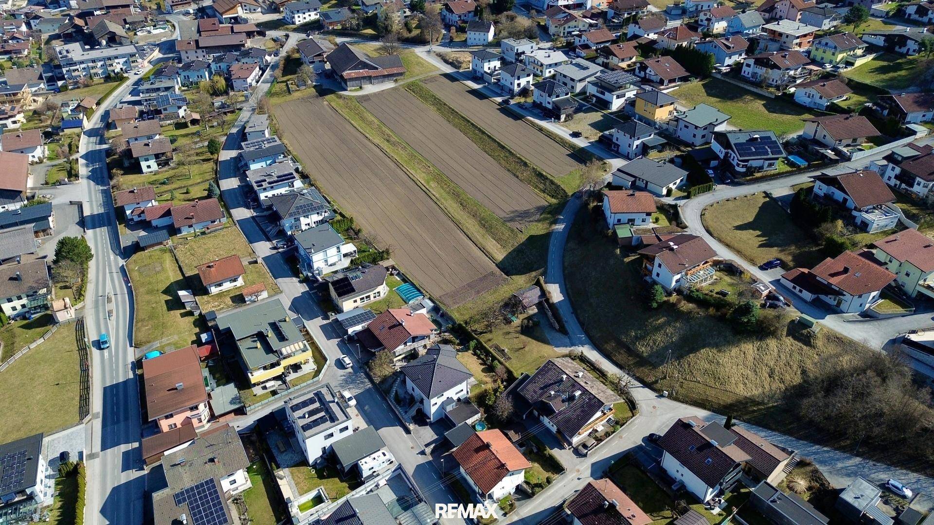 Weitläufige Luftaufnahme einer Wohnsiedlung mit Feldern und Straßen in einer ländlichen Umgebung.
