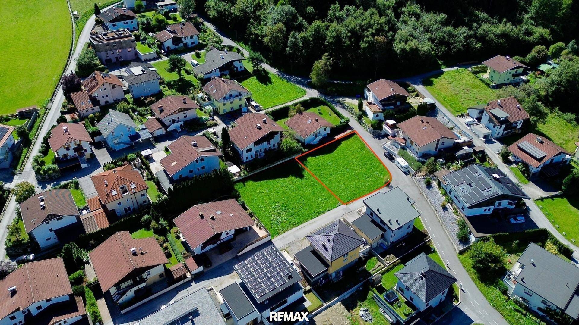Vogelperspektive eines freien Baugrundstücks, umgeben von Einfamilienhäusern und viel Grün.