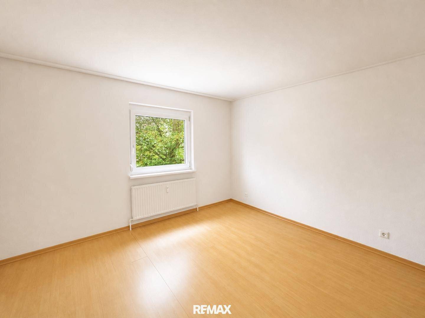 Helles Zimmer mit Parkettboden und Fenster mit grüner Aussicht, vielseitig nutzbar als Schlaf- oder Arbeitszimmer.