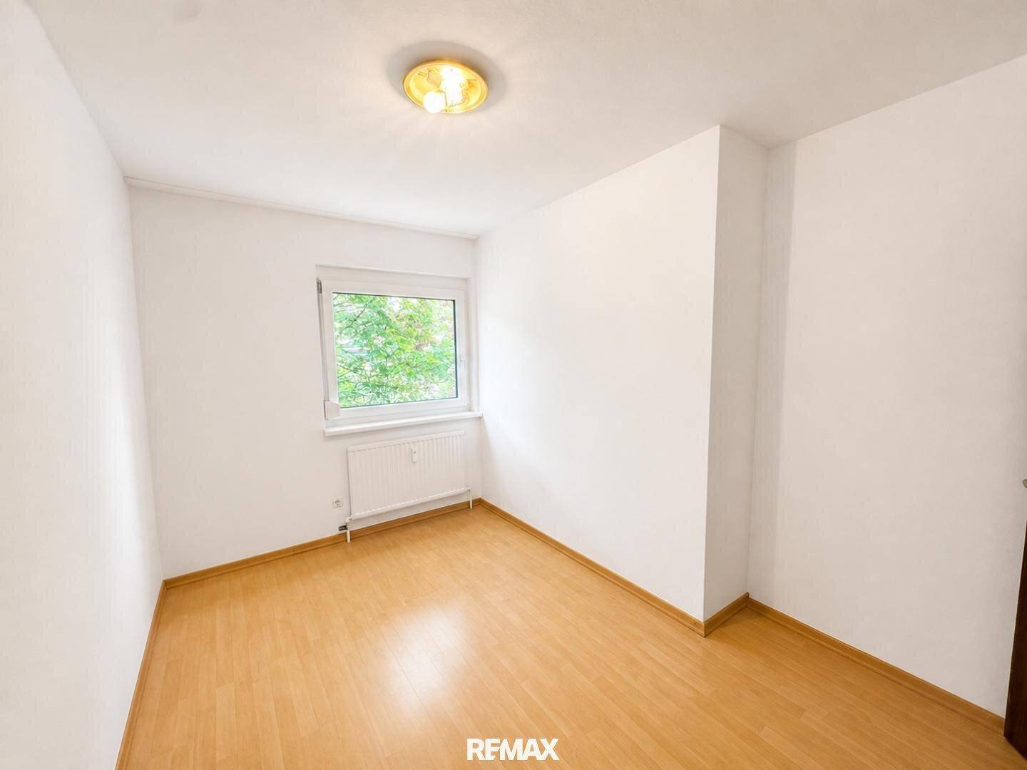 Gemütliches Schlafzimmer mit Parkettboden und Fenster mit Blick ins Grüne, ideal für Ruhe und Erholung.