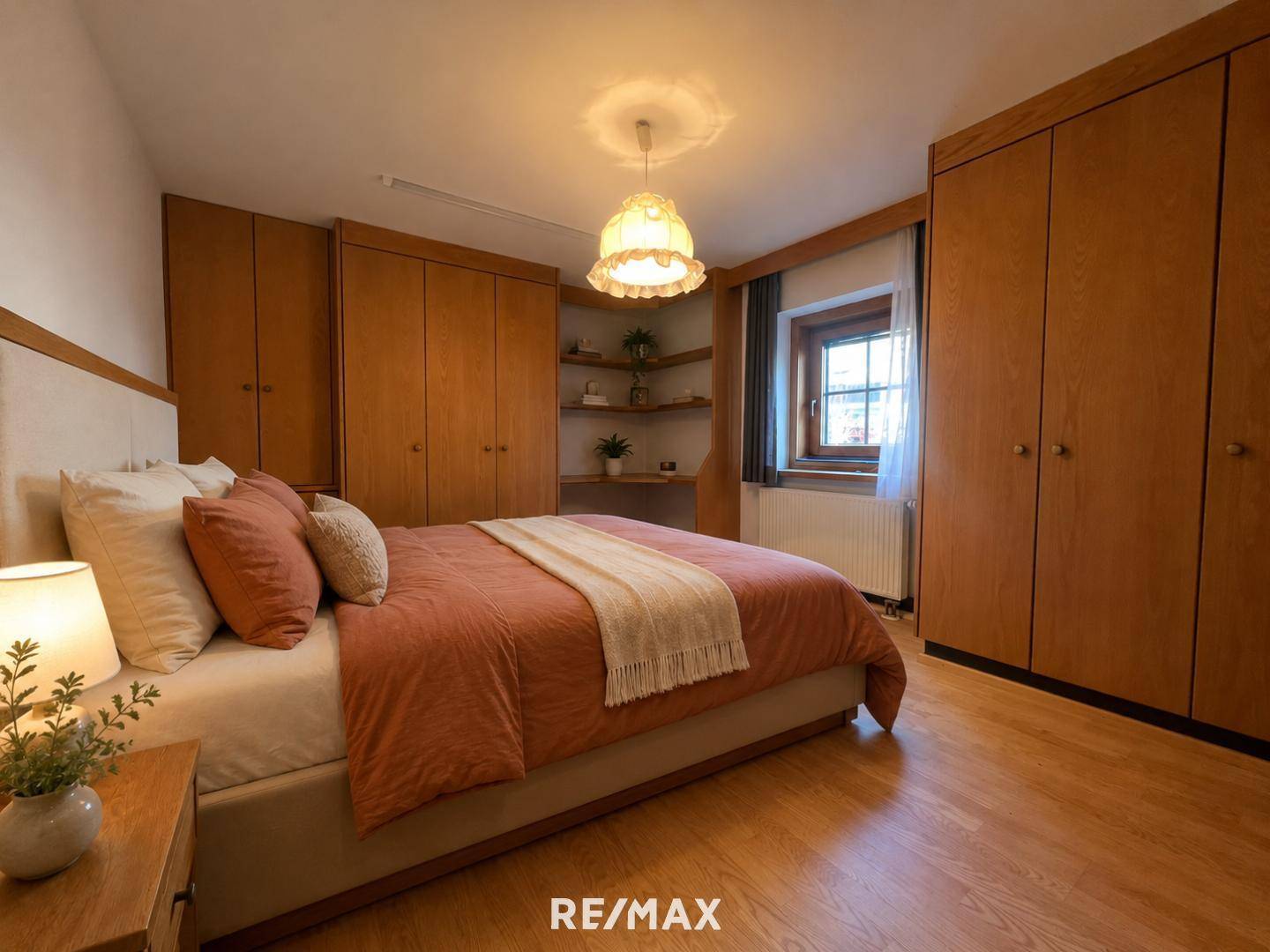 Gemütliches Schlafzimmer mit Holzeinbauschränken, warmem Licht und einem Fenster.