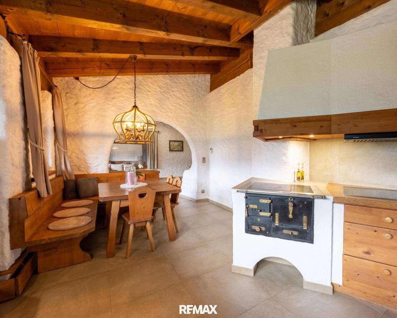 Traditionelle Küche im Landhausstil mit Holzmöbeln, Kachelofen und integriertem Essbereich.
