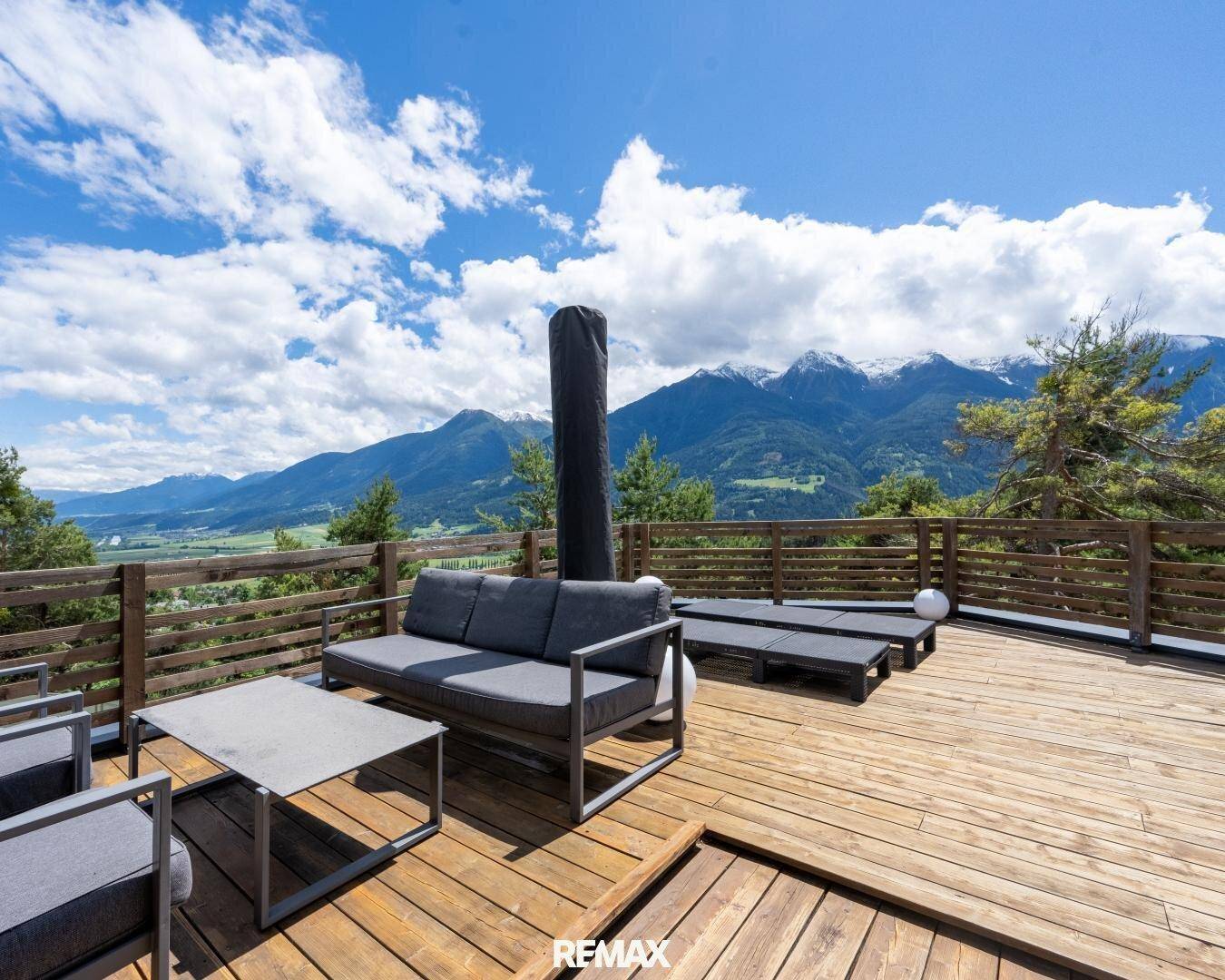Weitläufige Holzterrasse mit Loungemöbeln und atemberaubendem Panoramablick auf die Berge.