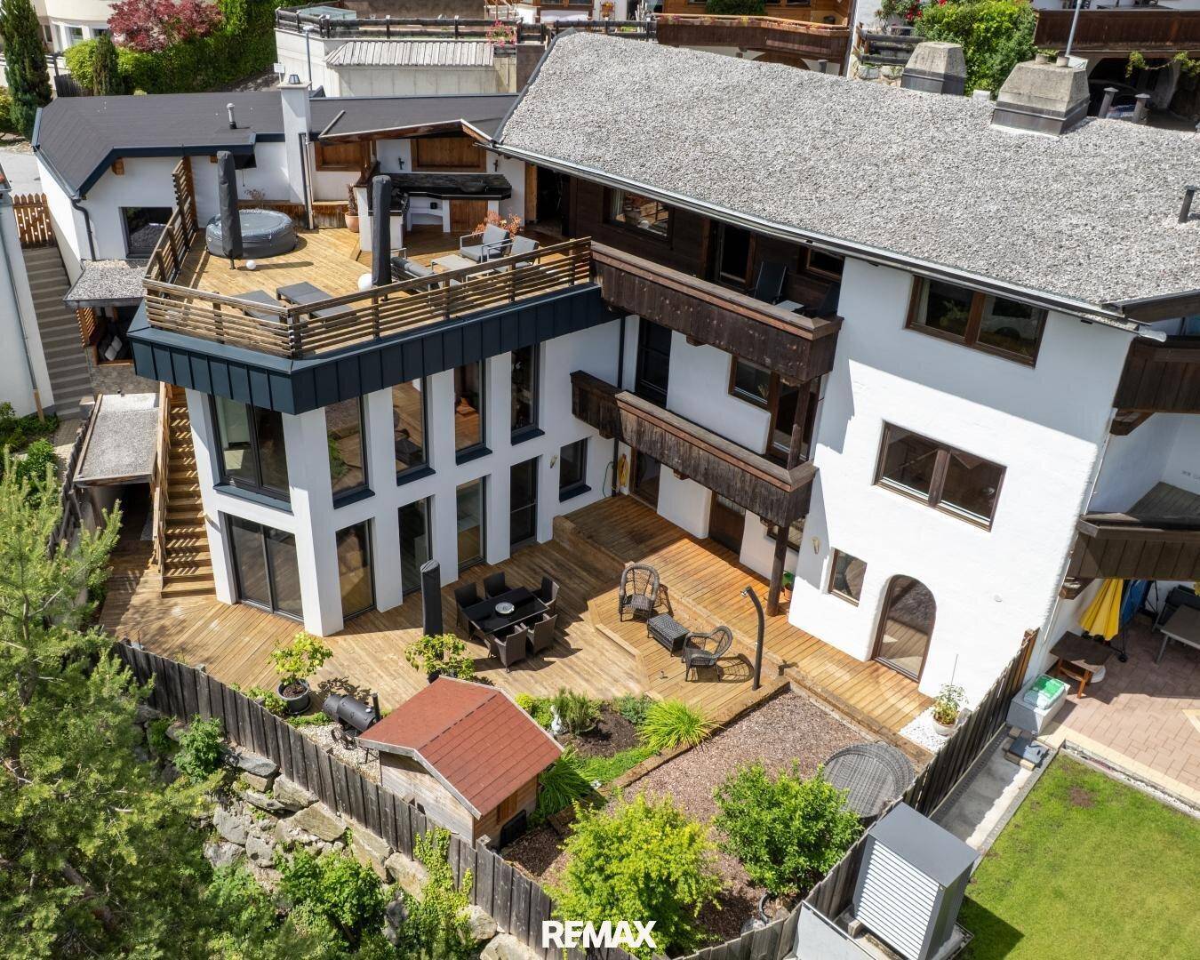 Gesamtansicht des modernen Hauses mit mehreren Terrassen, Garten und umliegender Natur.