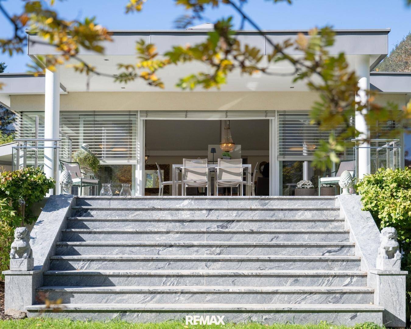 Beeindruckende Steintreppe führt zur großzügigen Terrasse der modernen Villa mit Bergblick.