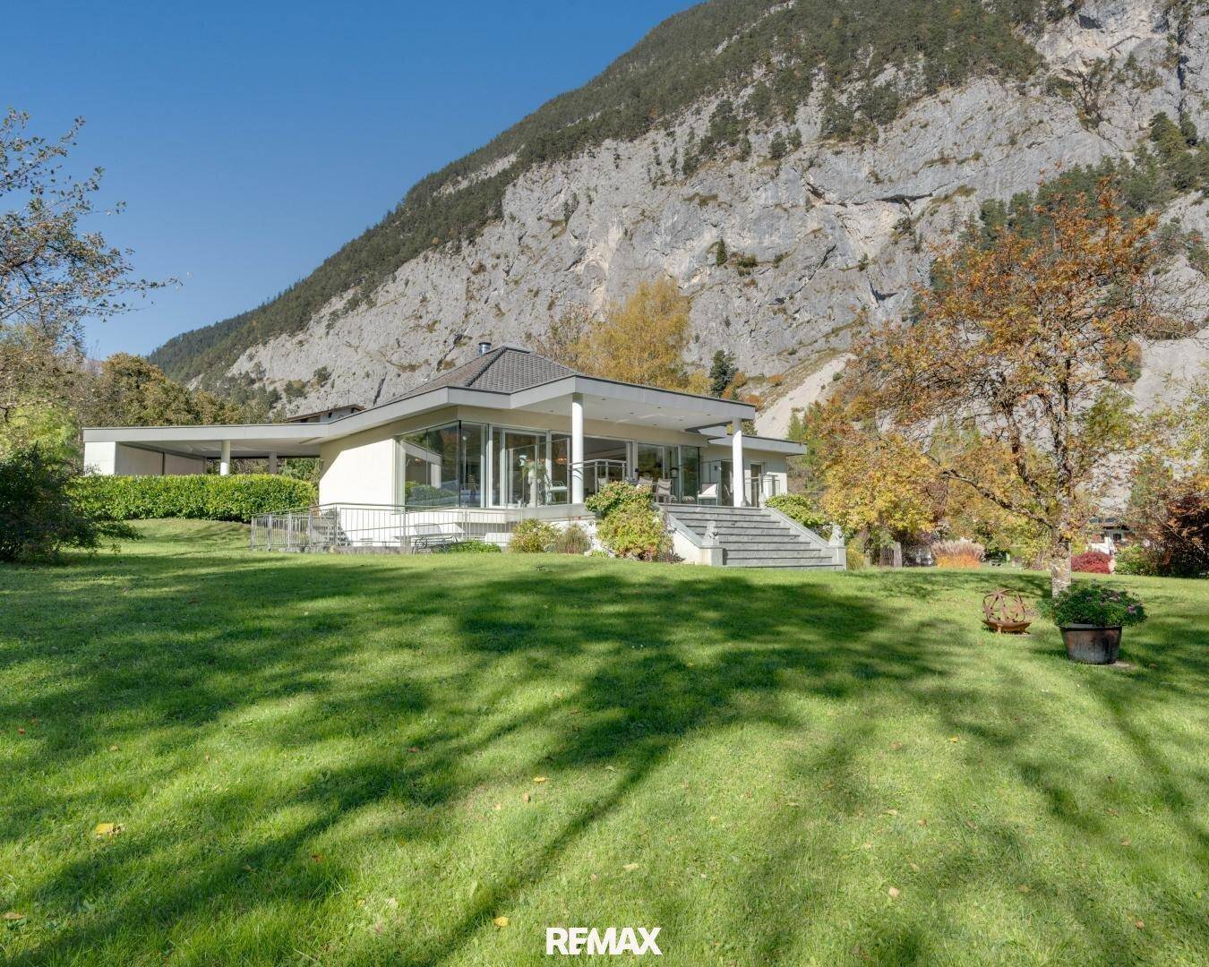 Beeindruckende Villa mit weitläufigem Garten und Blick auf die majestätische Felswand und die Berge.