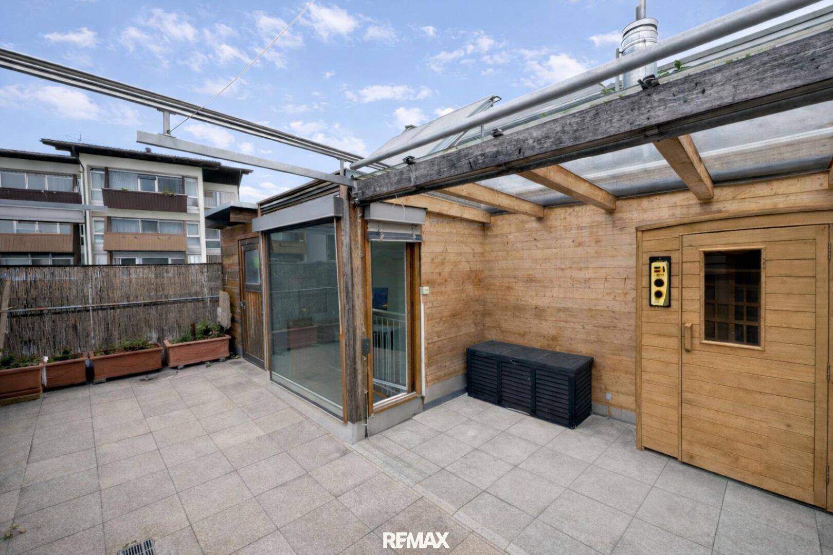 Dachterrasse mit privater Sauna, Fliesenboden und Blick auf die umliegenden Gebäude.