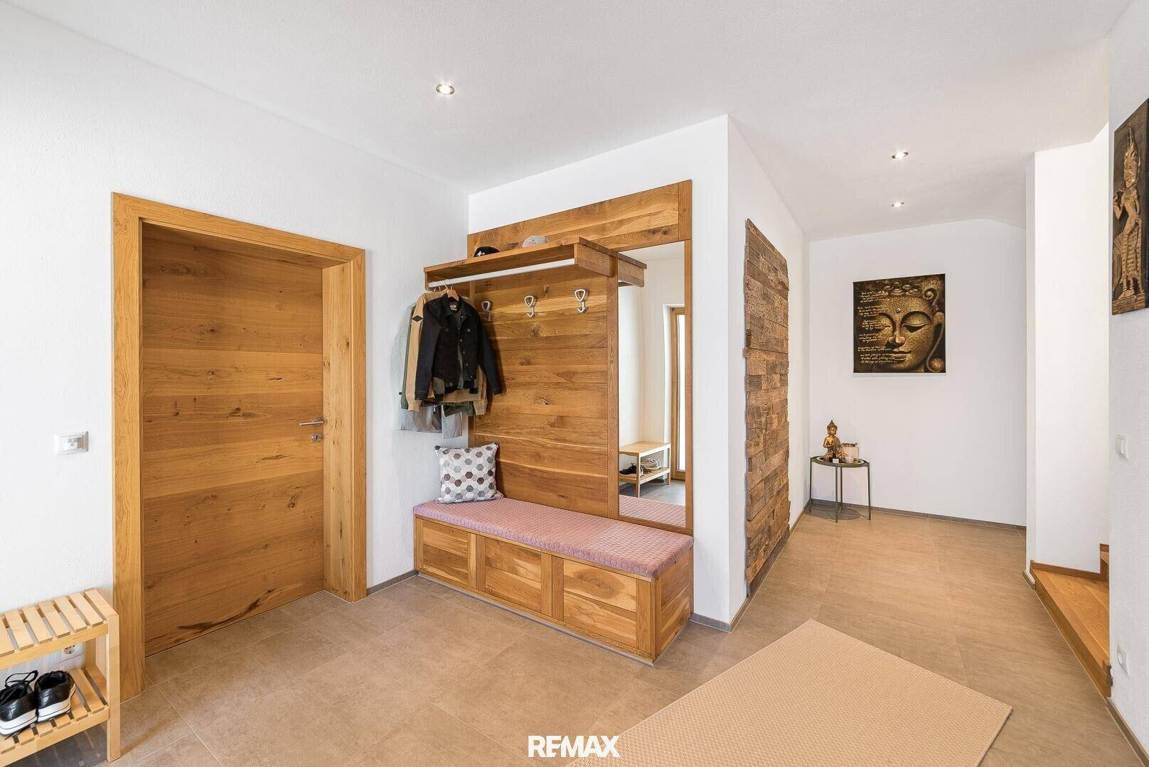 Heller Eingangsbereich mit Garderobe, Spiegel und Fliesenboden.