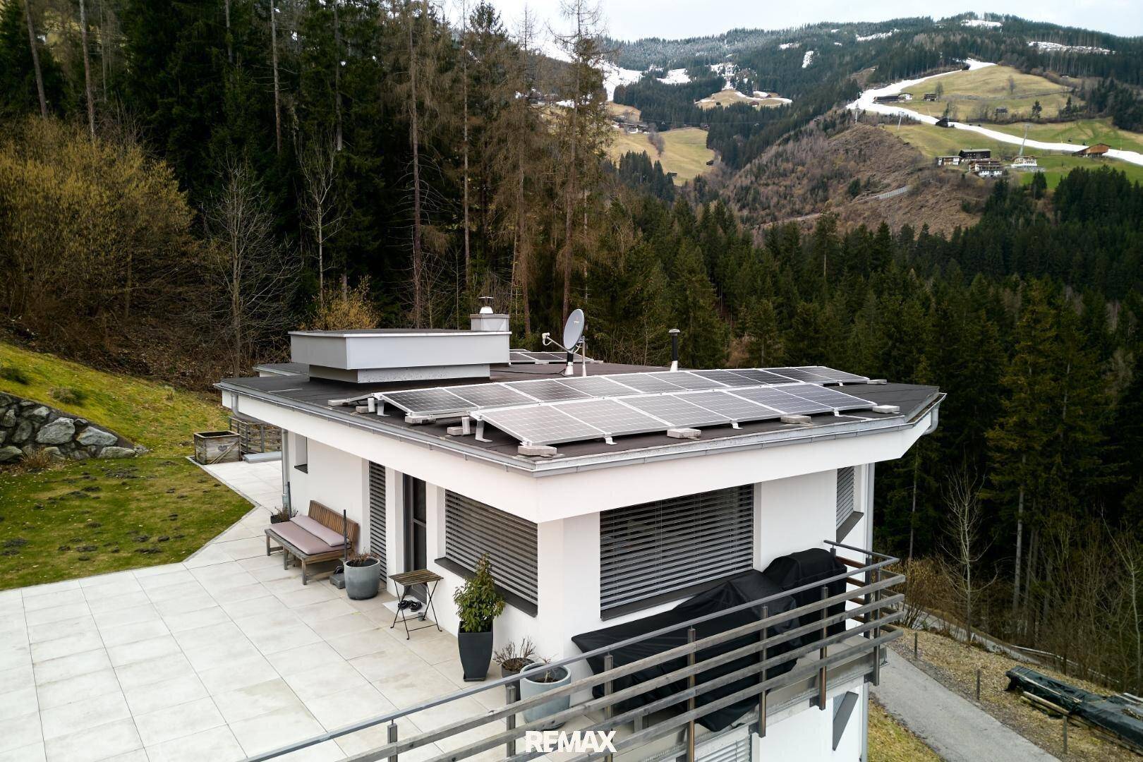 Panoramablick auf das moderne Haus mit Terrasse und die umliegende Berglandschaft.