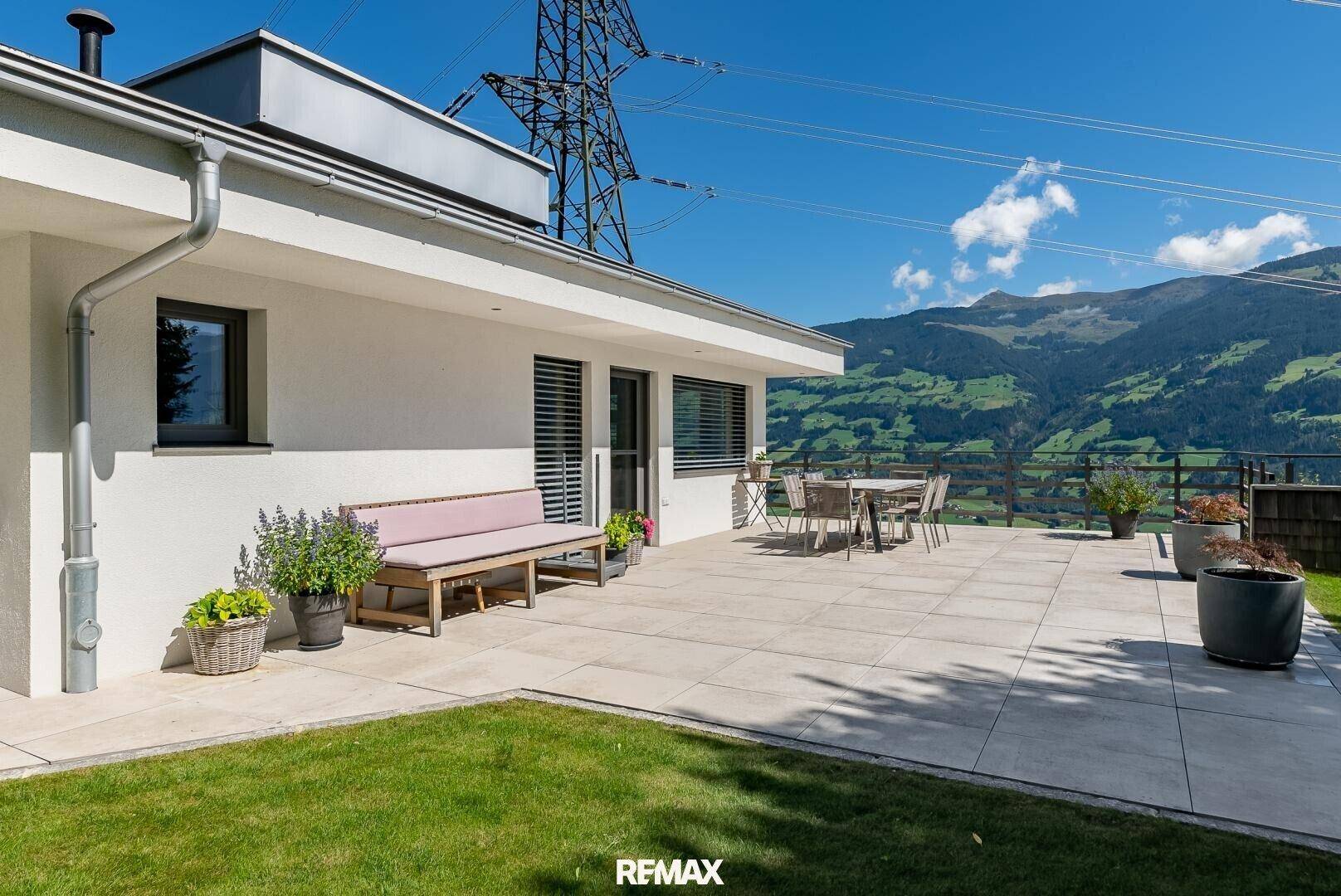 Sonniger Terrassenbereich mit Sitzgelegenheiten und weitem Blick auf die Bergwelt.