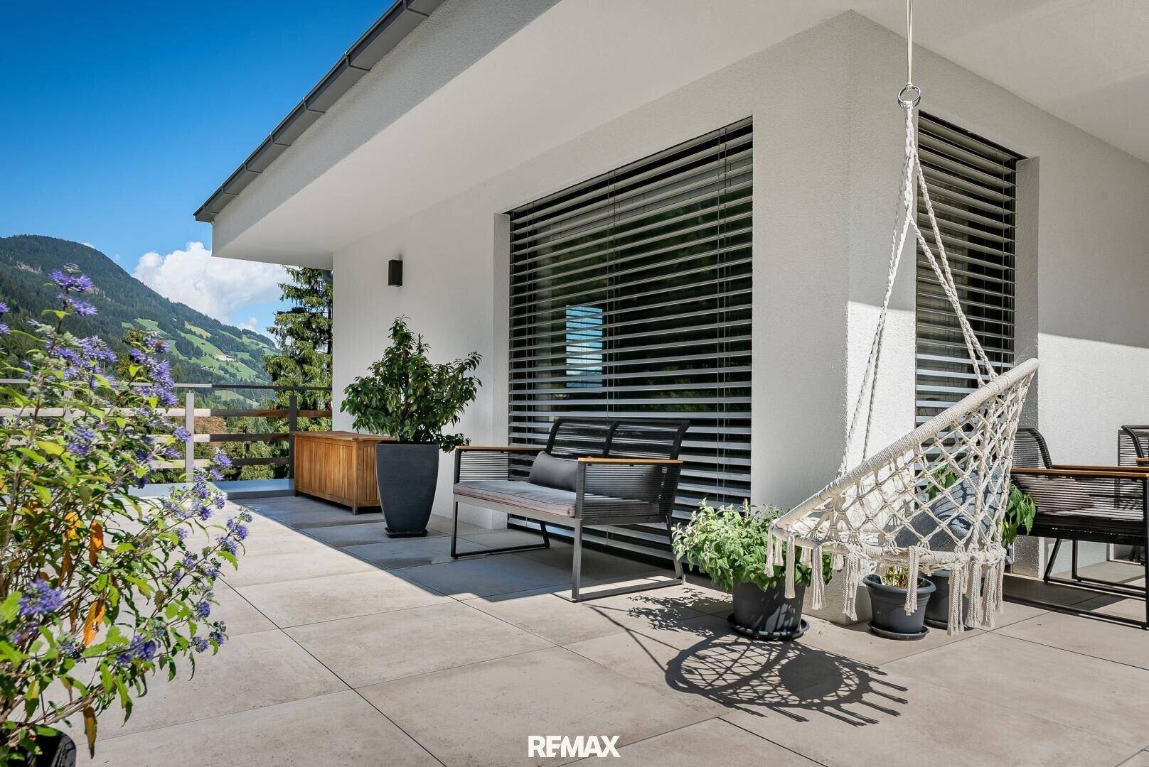Entspannende Terrasse mit Hängesessel, Pflanzen und Panoramablick auf die umliegende Natur.