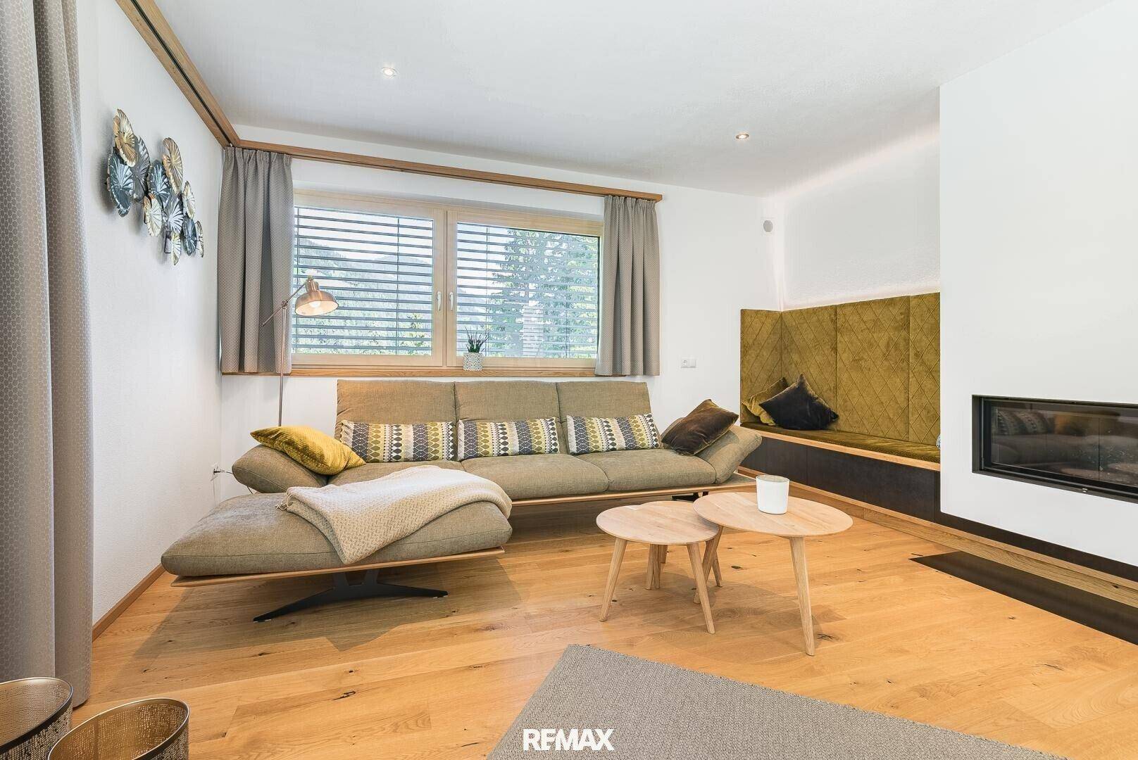 Helles Wohnzimmer mit modernem Sofa, Holzboden und integriertem Kamin für gemütliche Abende.
