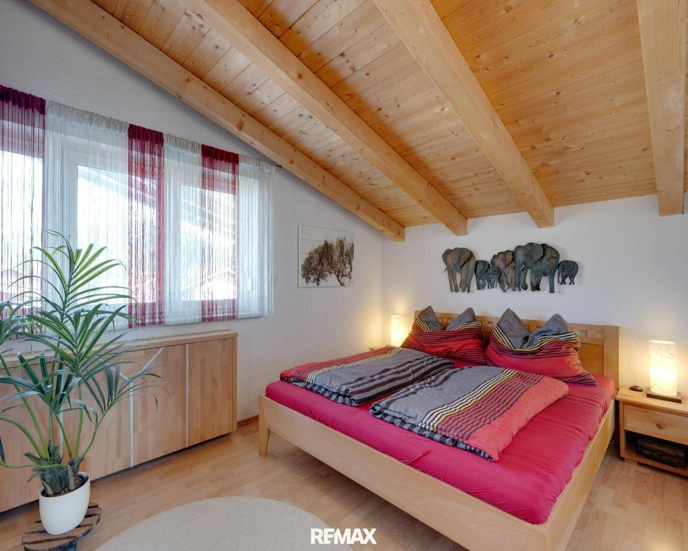Gemütliches Schlafzimmer mit Holzbalkendecke, Holzmöbeln und natürlichem Licht.