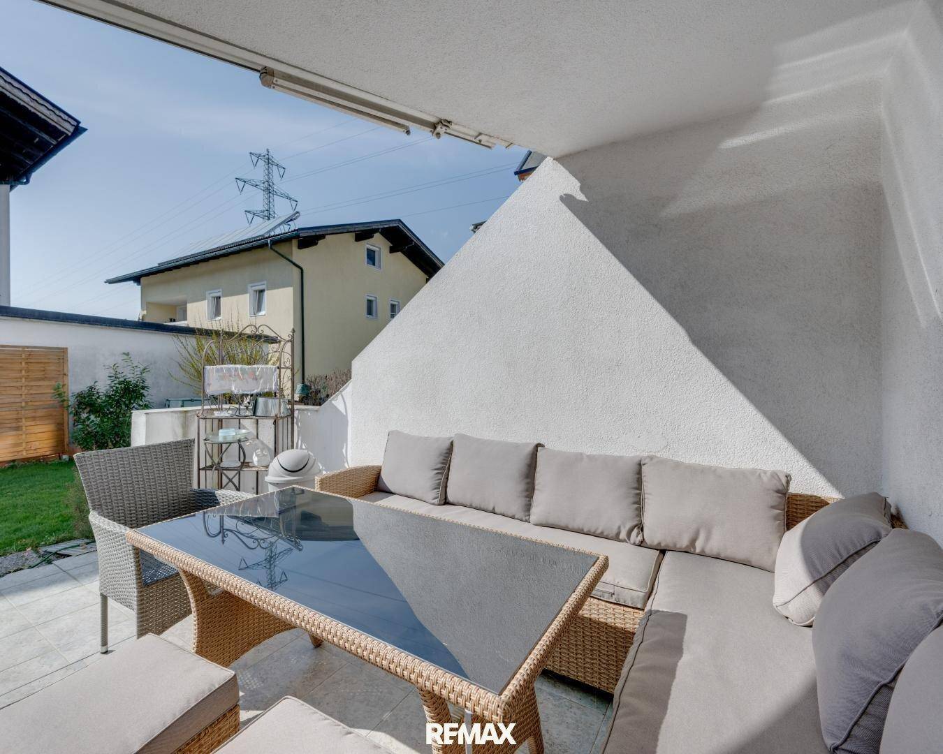 Überdachte Terrasse mit bequemen Gartenmöbeln und Blick auf den angrenzenden Rasenbereich.