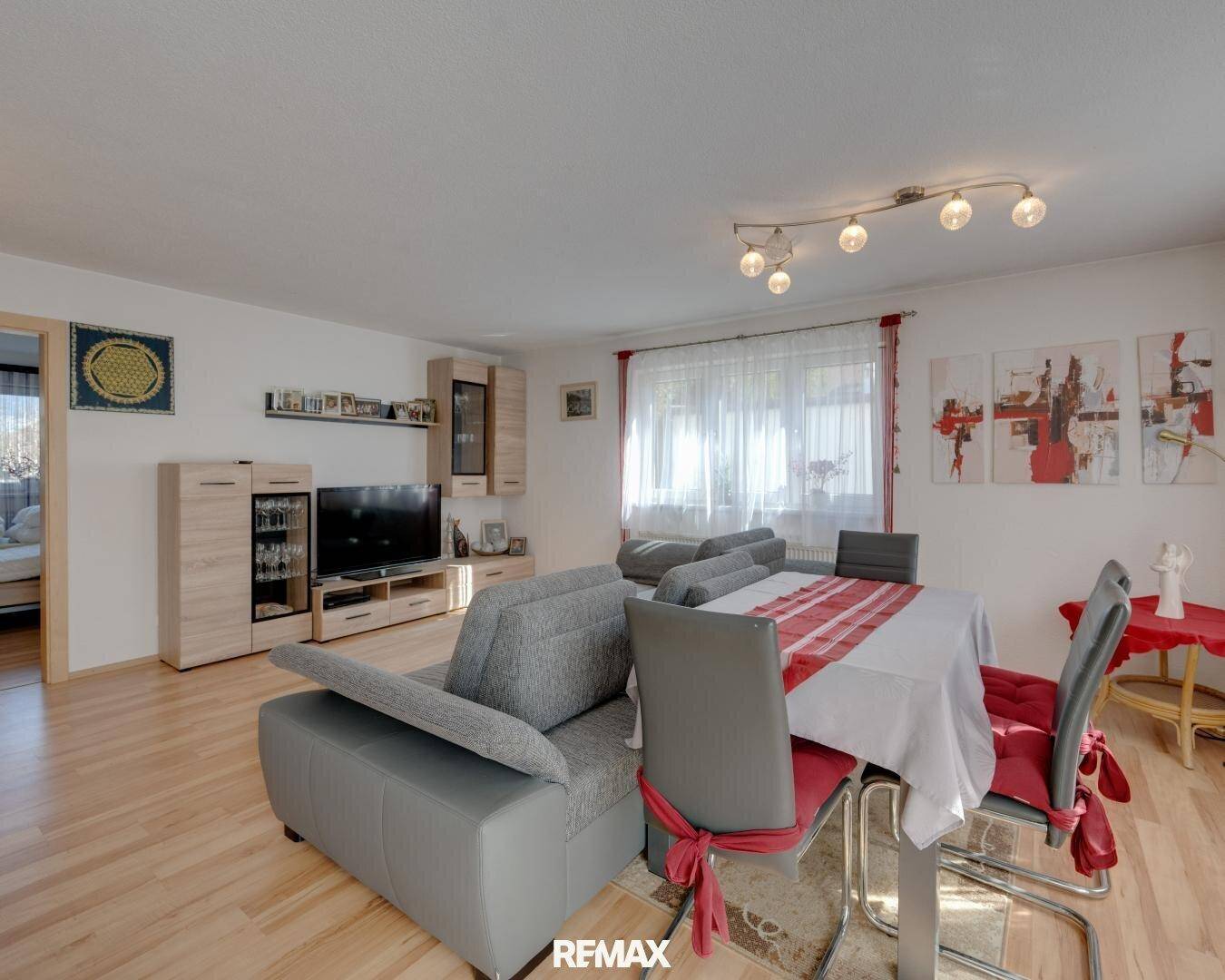 Heller Wohn-Essbereich mit modernem Sofa, Esstisch und hellem Holzfußboden.