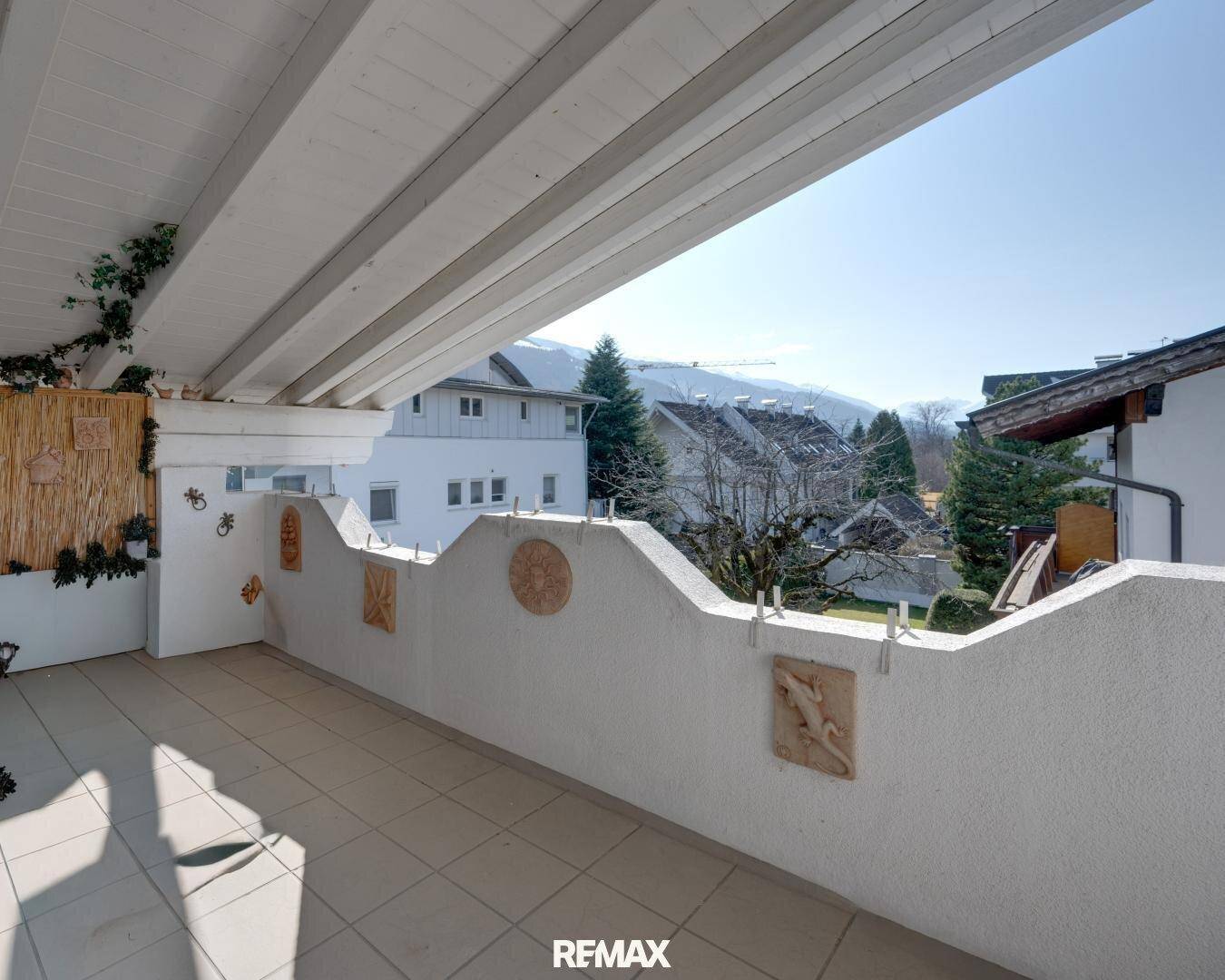 Überdachter Balkon mit dekorativen Elementen und weitem Blick auf die Berglandschaft.