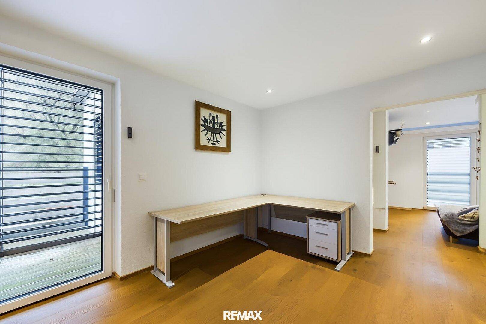 Helles Arbeitszimmer mit Schreibtisch und direktem Zugang zu einem Balkon.