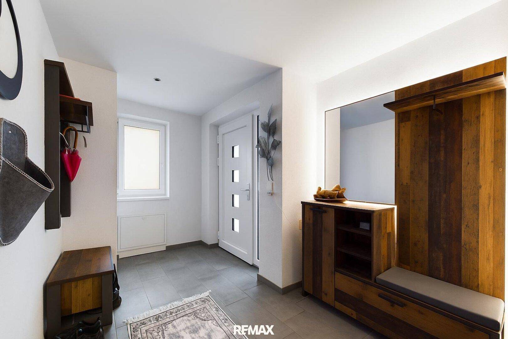 Gemütlicher Eingangsbereich mit Holzelementen, Garderobe und Fliesenboden.