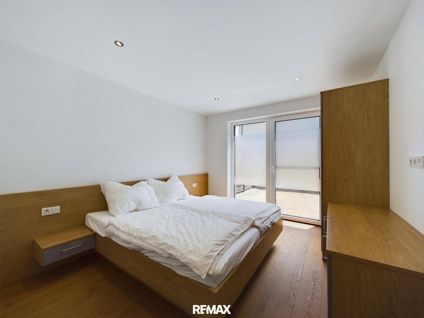 Helles Schlafzimmer mit Doppelbett, Holzboden und direktem Zugang zur Terrasse.