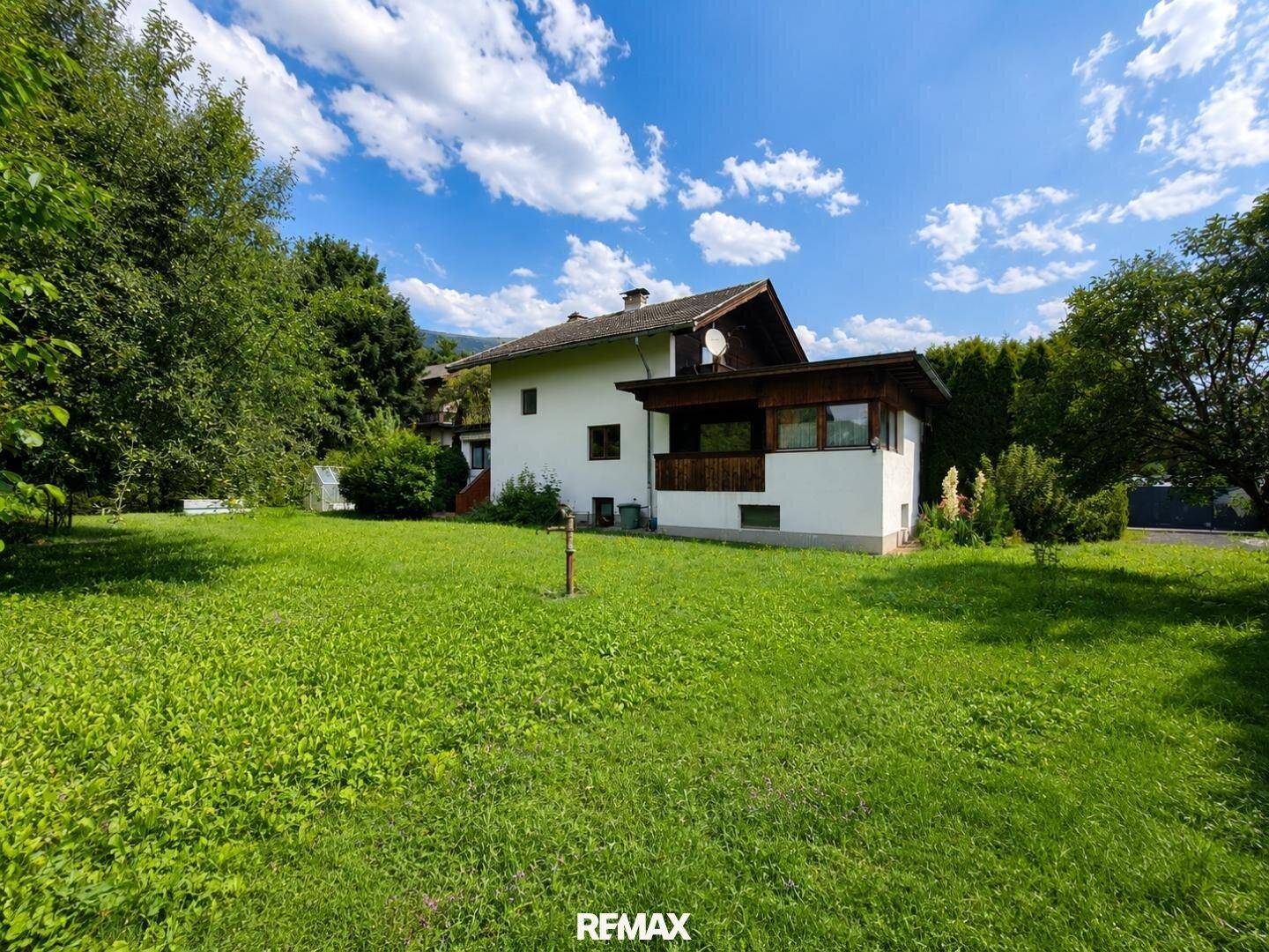 Ruhiger Gartenbereich mit weitläufiger Rasenfläche und überdachtem Balkon am Haus.