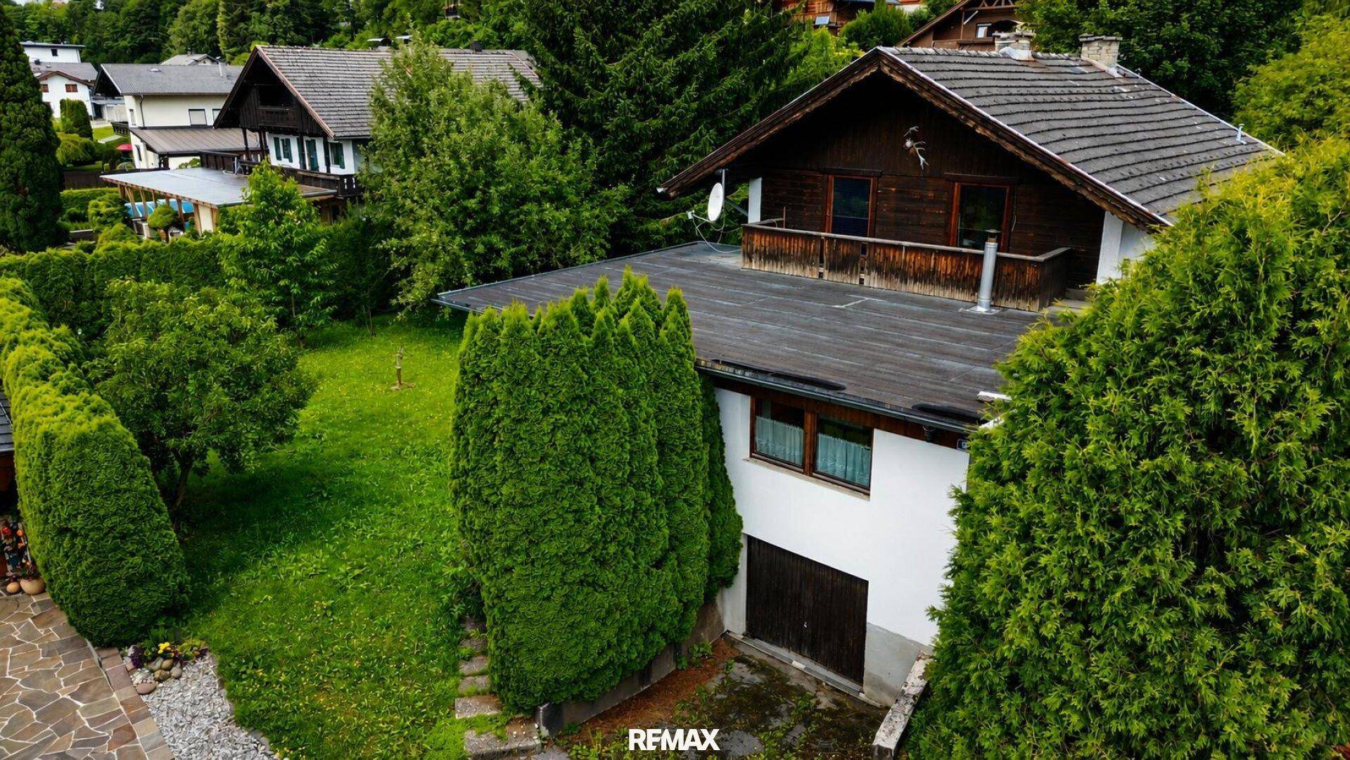 Dachansicht des Hauses mit Garage, umgeben von hohen Hecken und weiteren Wohnhäusern.