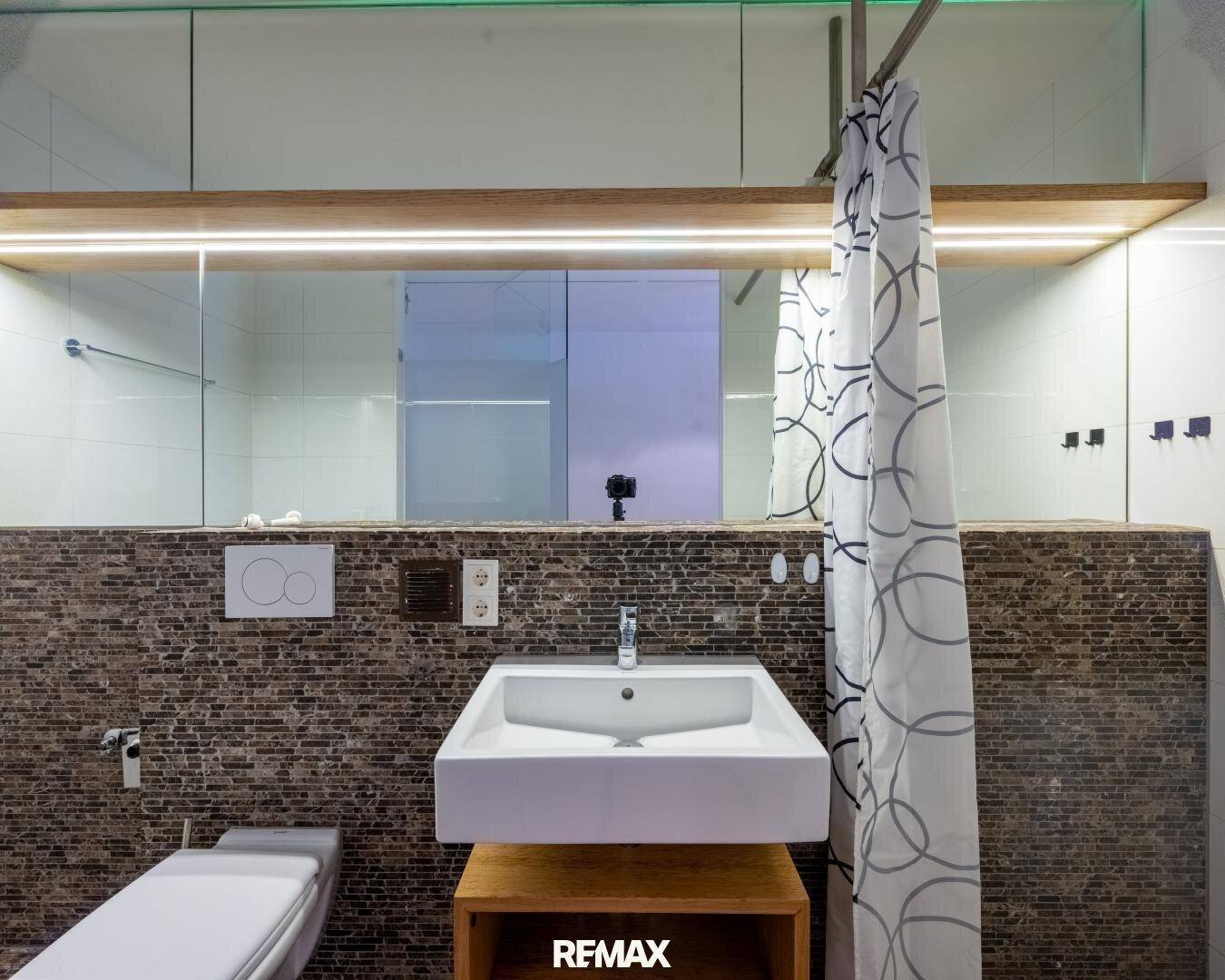 Modernes Badezimmer mit Mosaikfliesen, wandhängendem WC und stilvollem Waschbecken.