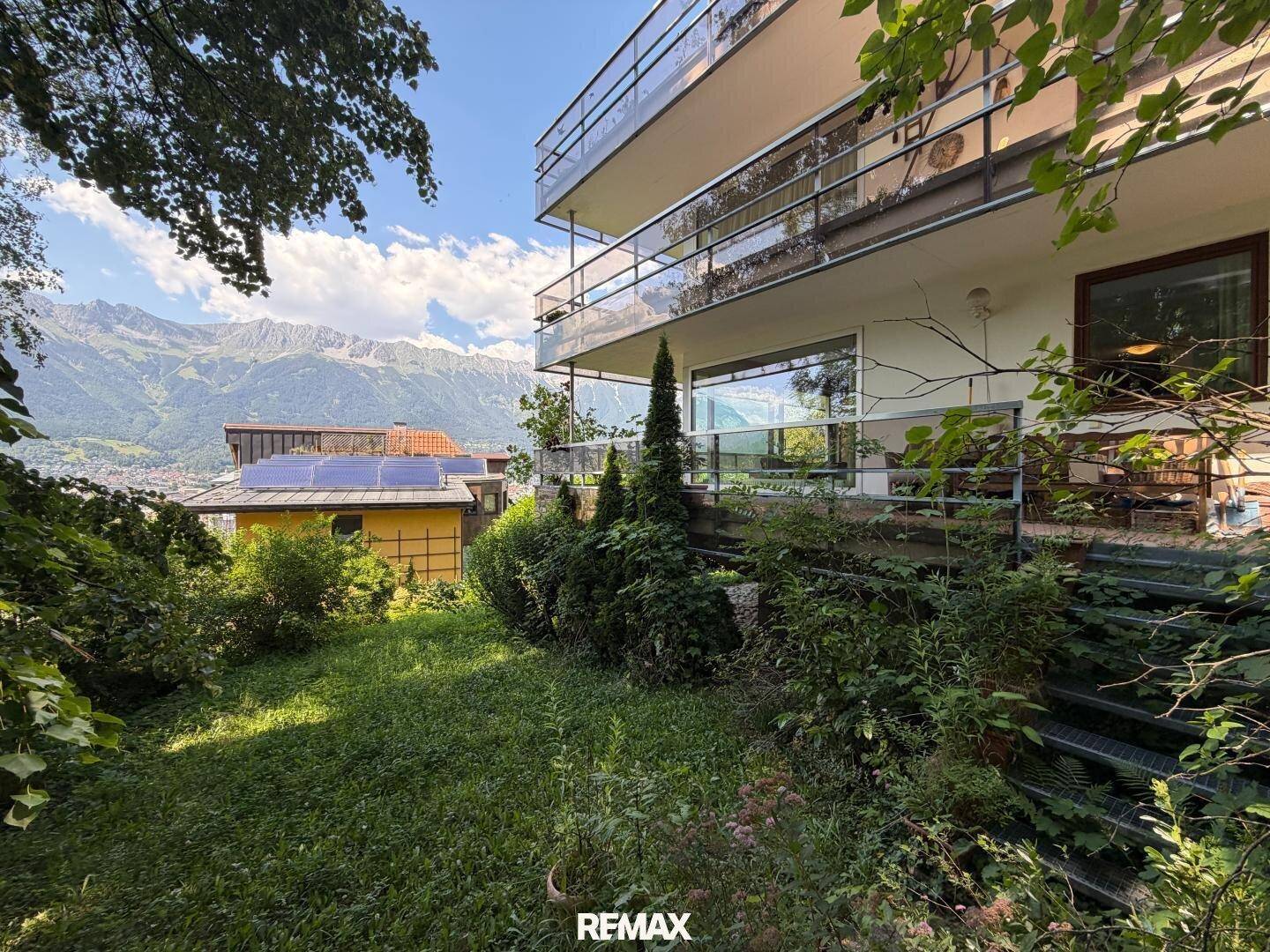 Gepflegter Gartenbereich mit üppiger Vegetation und Blick auf die umliegende Berglandschaft.