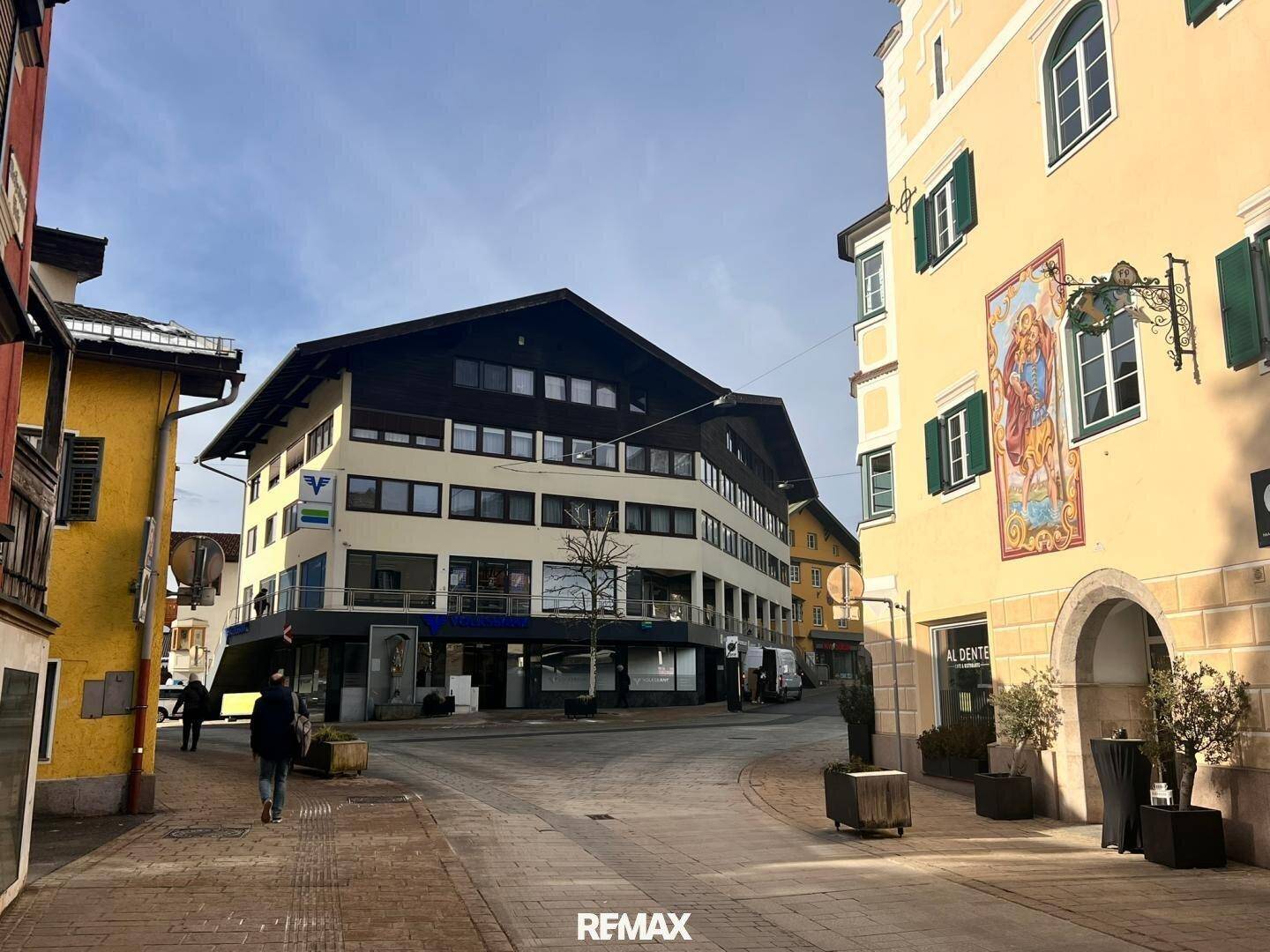 Historische Gebäude in einer belebten Stadtstraße mit traditioneller Architektur und Geschäften im Erdgeschoss.