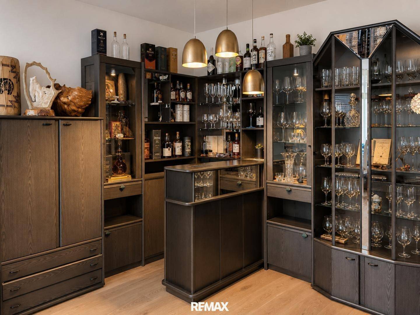 Elegante Vitrinen mit Gläsern und Flaschen, beleuchtet von goldenen Pendelleuchten.