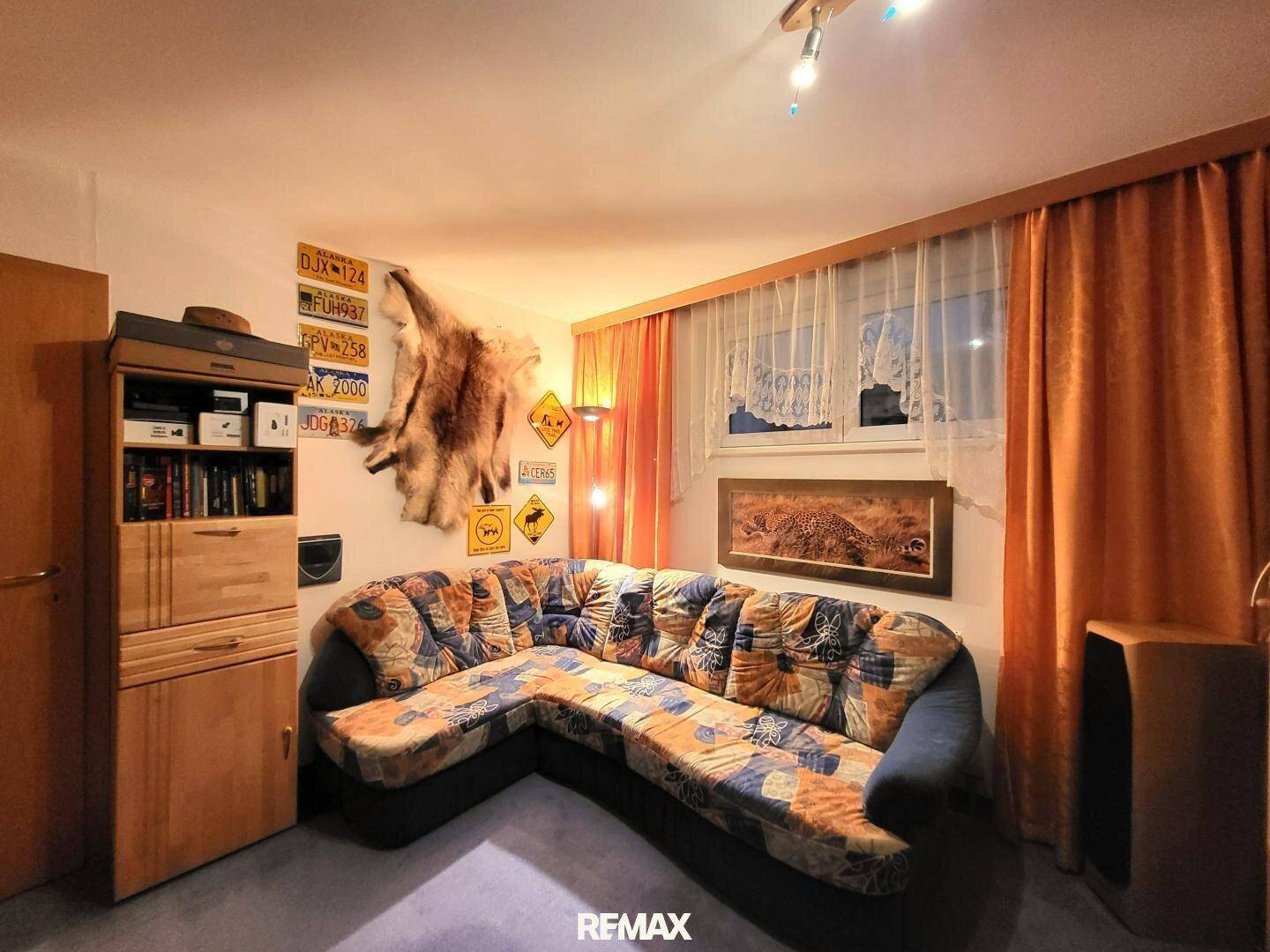 Rustikales Wohnzimmer mit Ecksofa, Holzmöbeln und Tierfell-Dekoration.