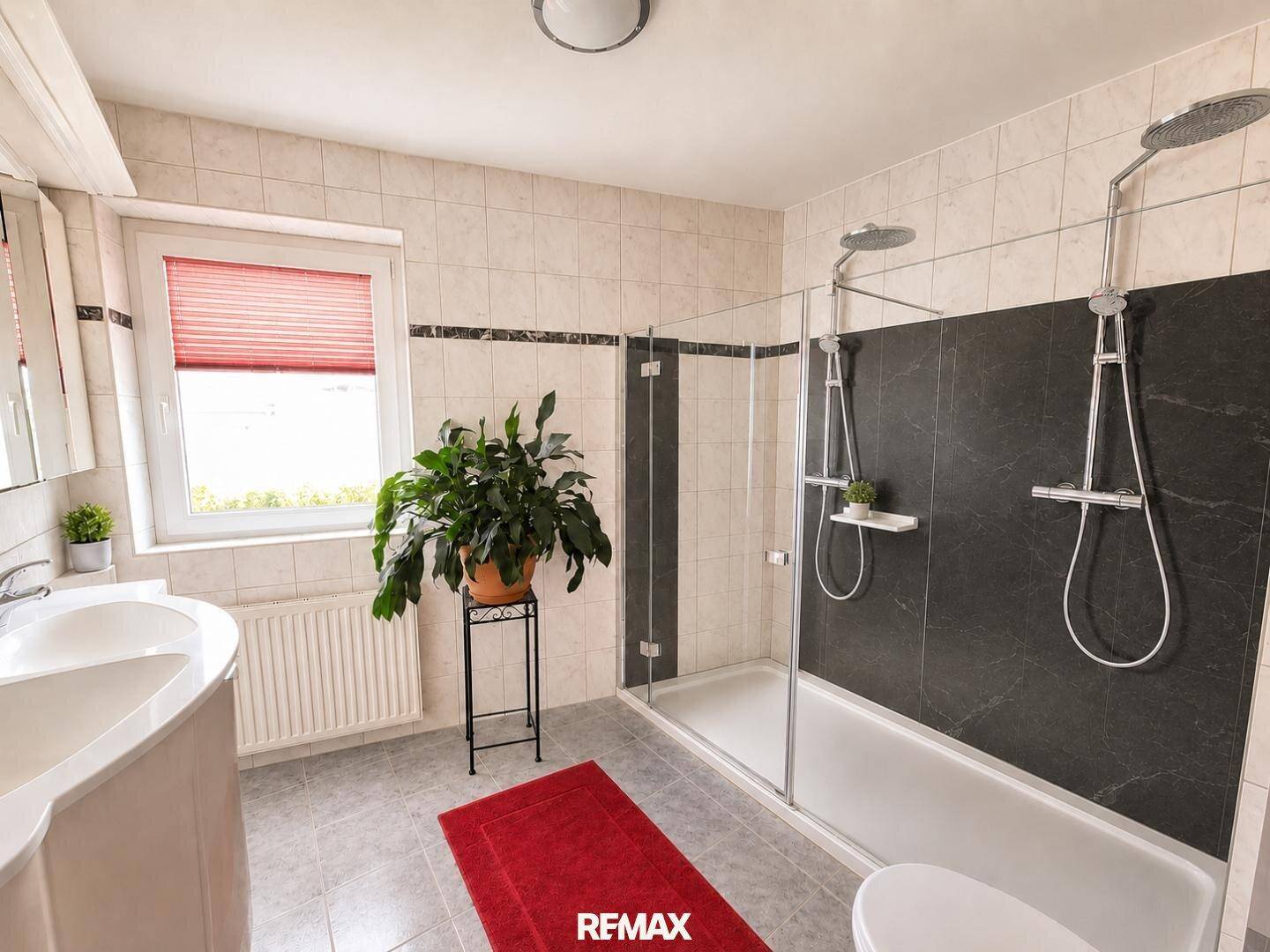 Modernes Badezimmer mit Dusche, Badewanne, Fenster und großformatigen Fliesen.