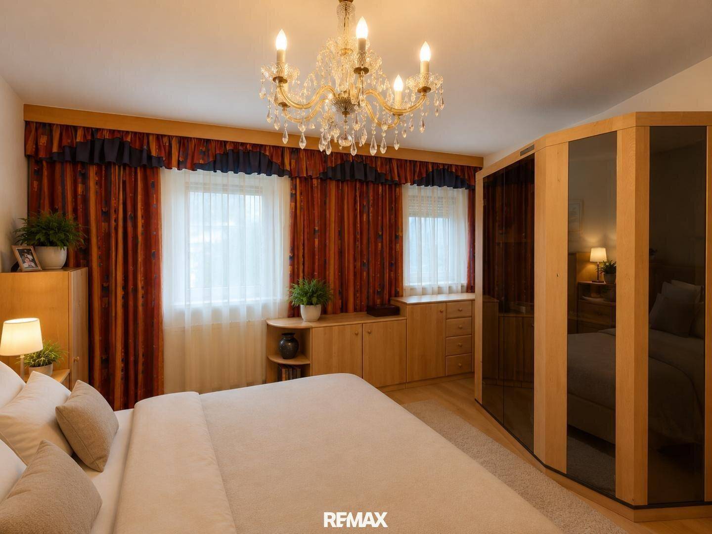 Schlafzimmer mit Doppelbett, Holzmöbeln und elegantem Kronleuchter.