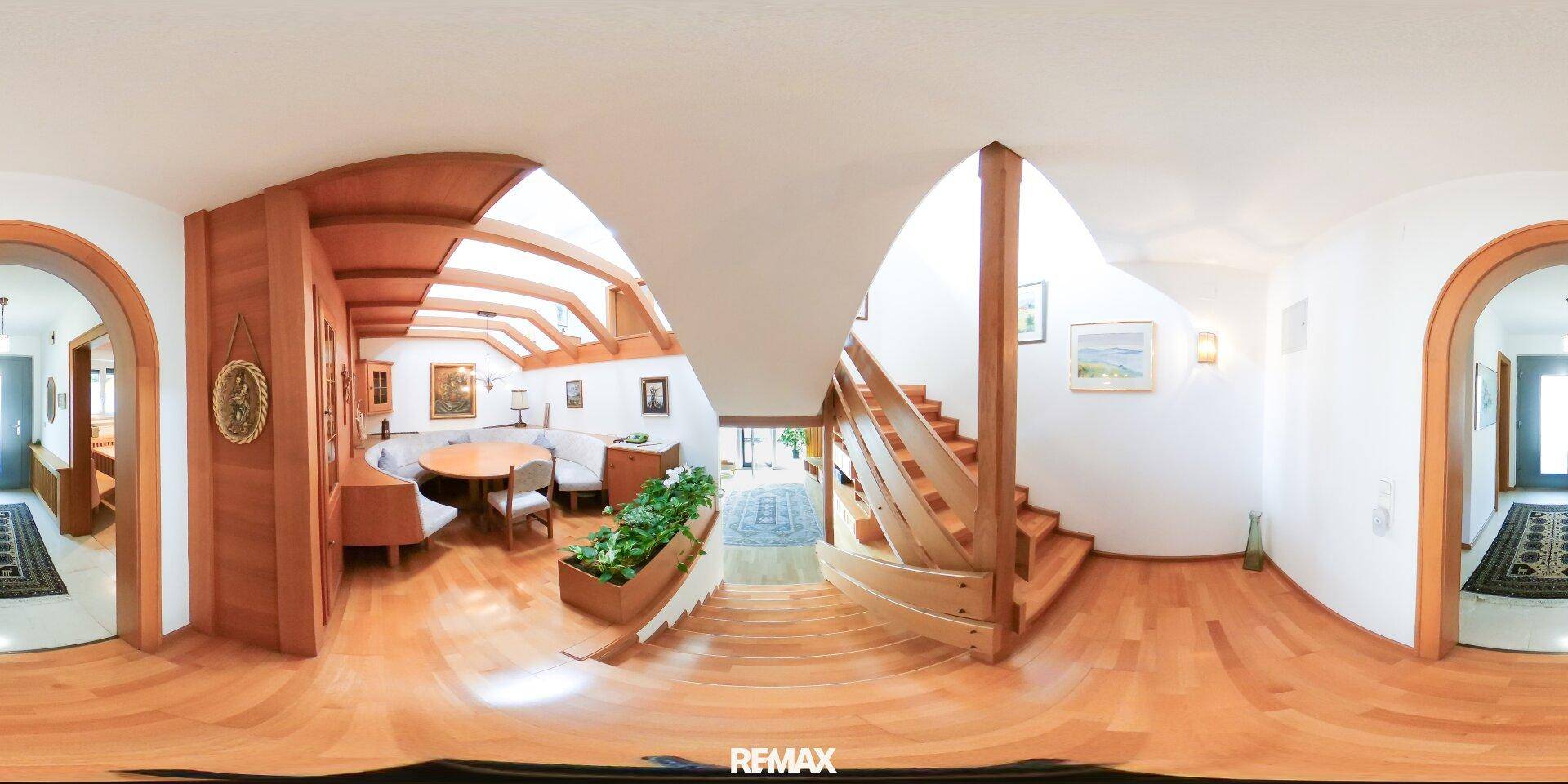 Panoramablick auf den offenen Treppenbereich mit Holzgeländer und hohen Decken.