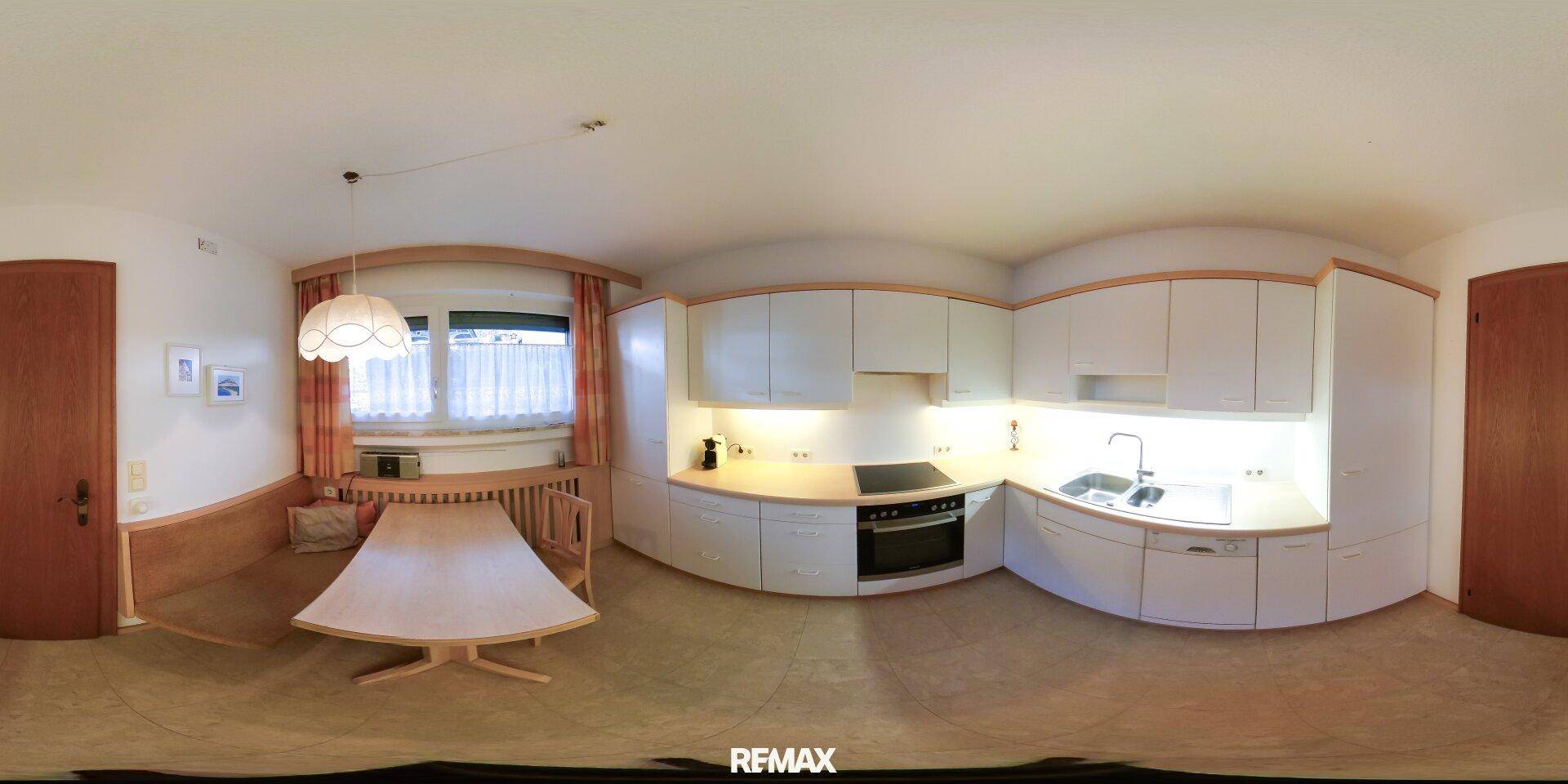 Panoramablick auf die funktionale Küche mit weißen Schränken und Essbereich.