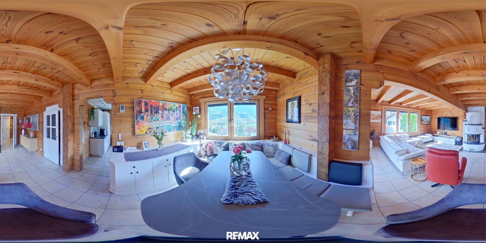 Essbereich im Holzhaus mit großem Esstisch, moderner Beleuchtung und weitem Blick ins Grüne.