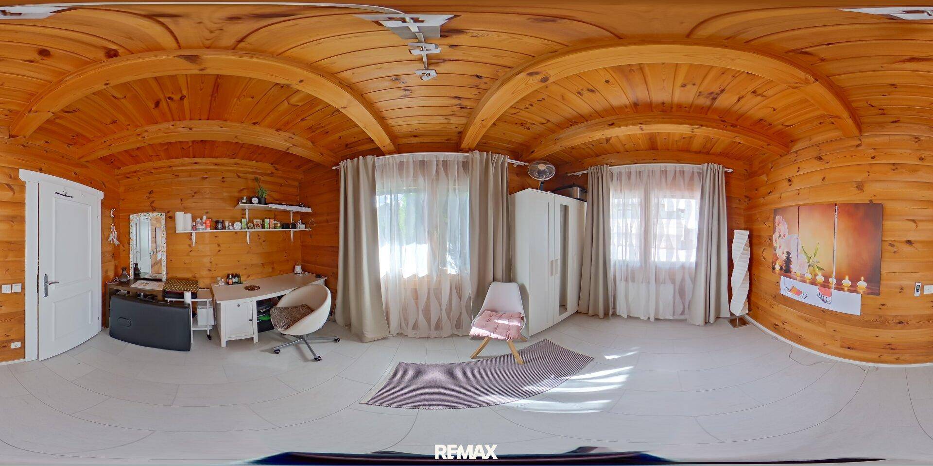 Helles Büro oder Gästezimmer mit Holzwänden, Schreibtisch und zwei großen Fenstern.