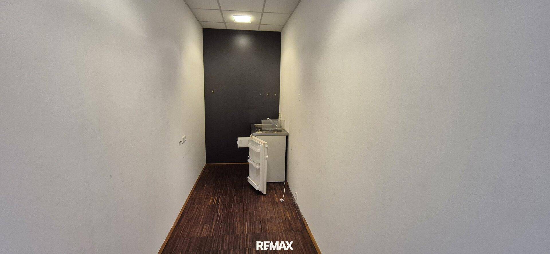 Schmaler Flur oder Hauswirtschaftsraum mit dunklem Boden und einer Waschmaschine.